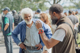 Two men converse outdoors among a crowd