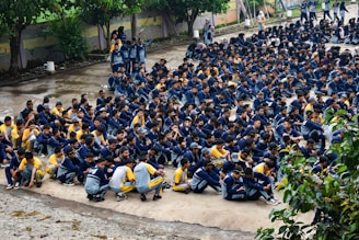 Many students are gathered outside, sitting down.