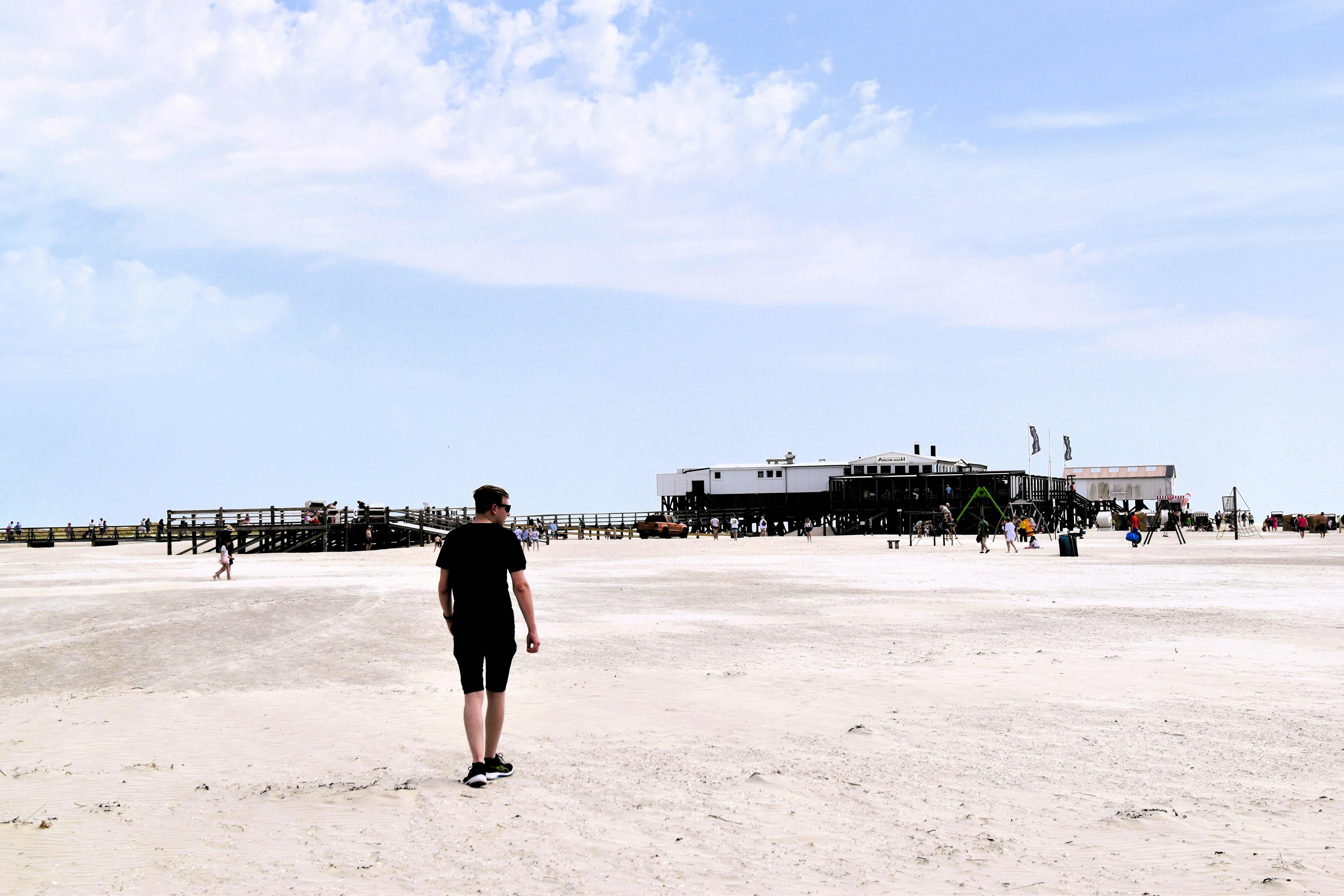 A man walks away on a sandy beach.
