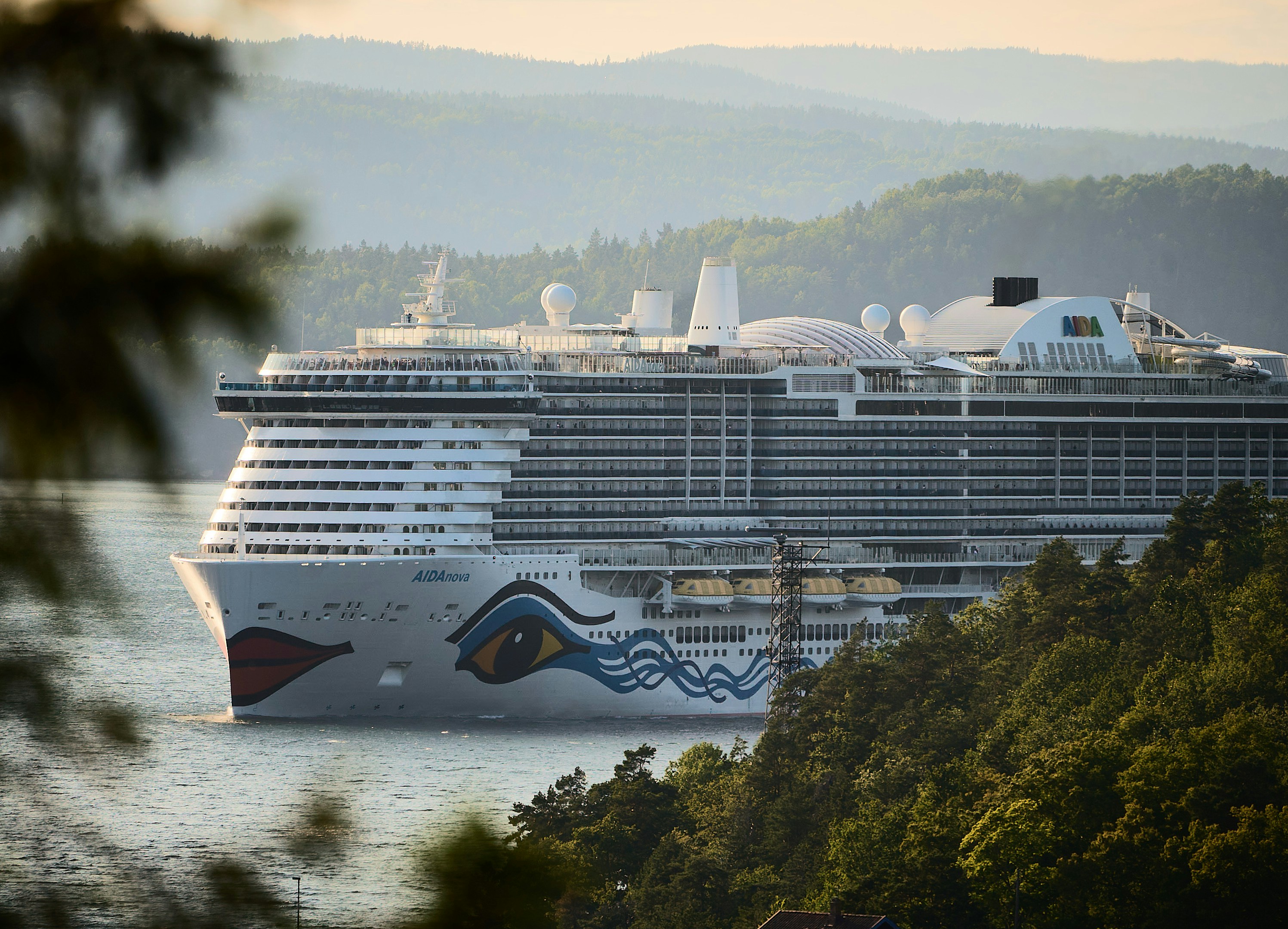 A cruise ship sails amidst mountains.