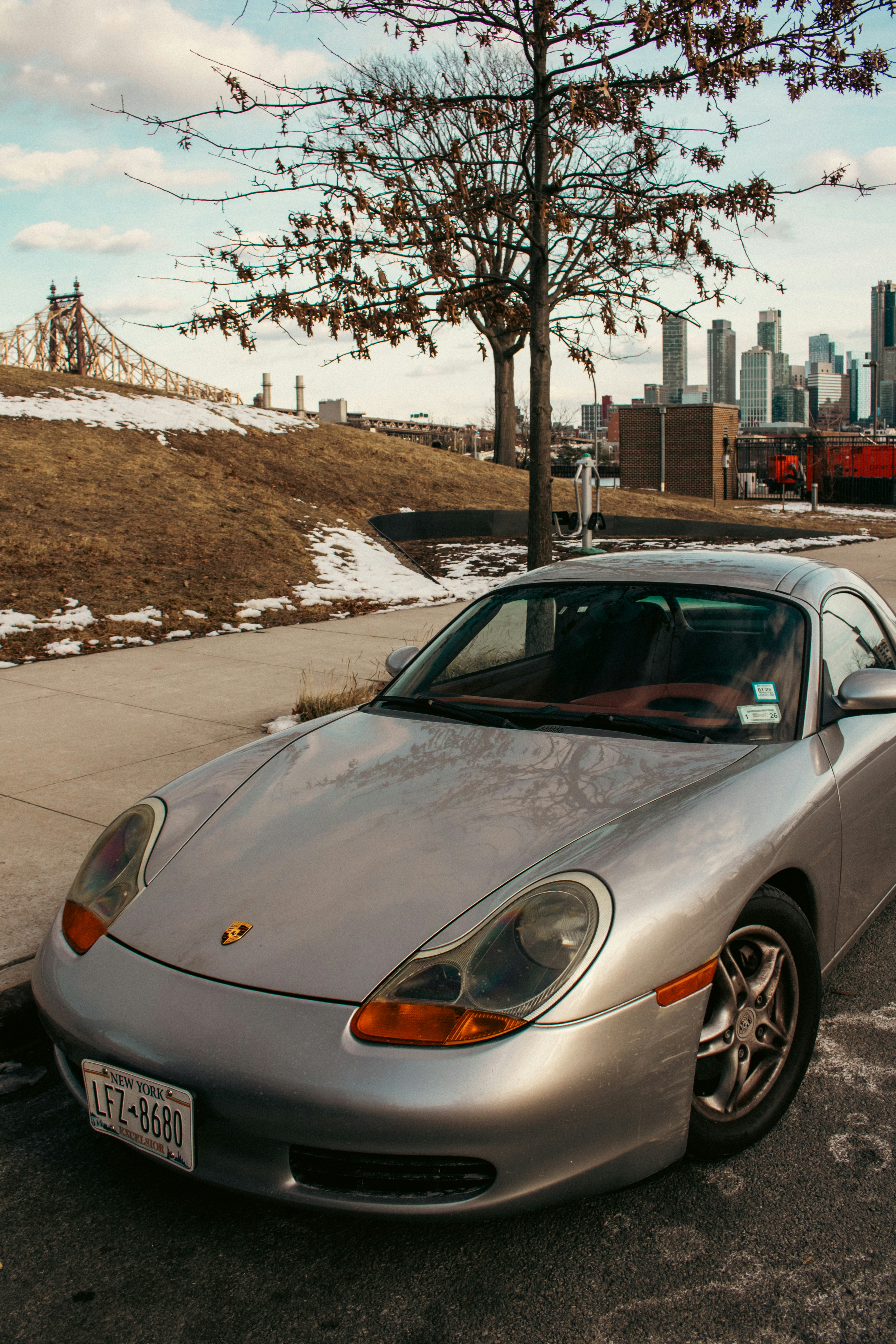 Silver porsche parked with city and bridge views.
