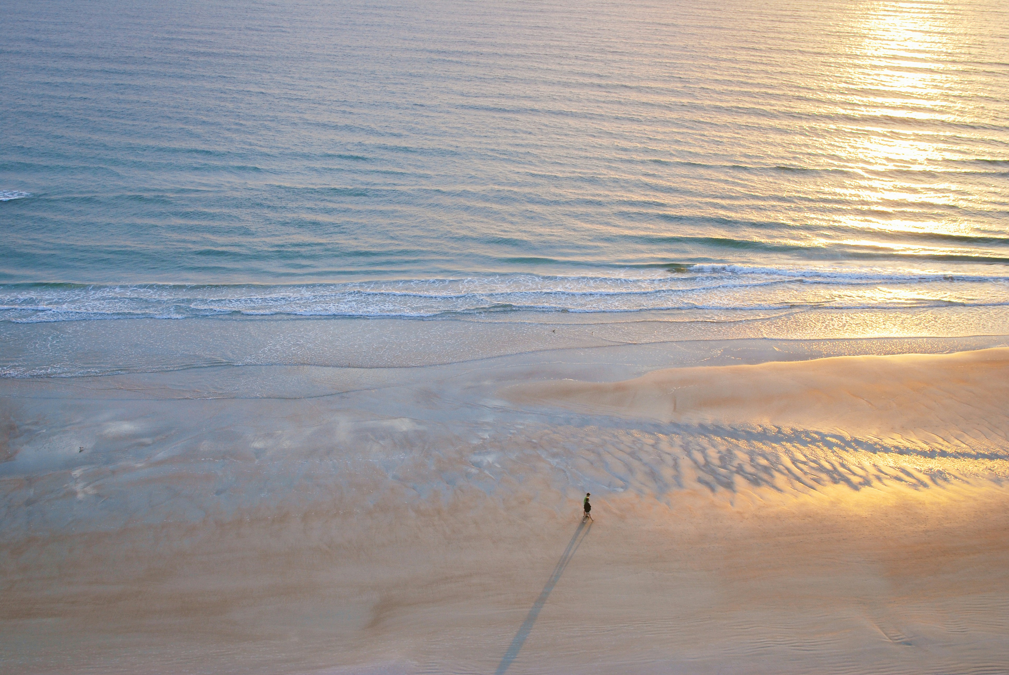 A person walks alone on a beach.