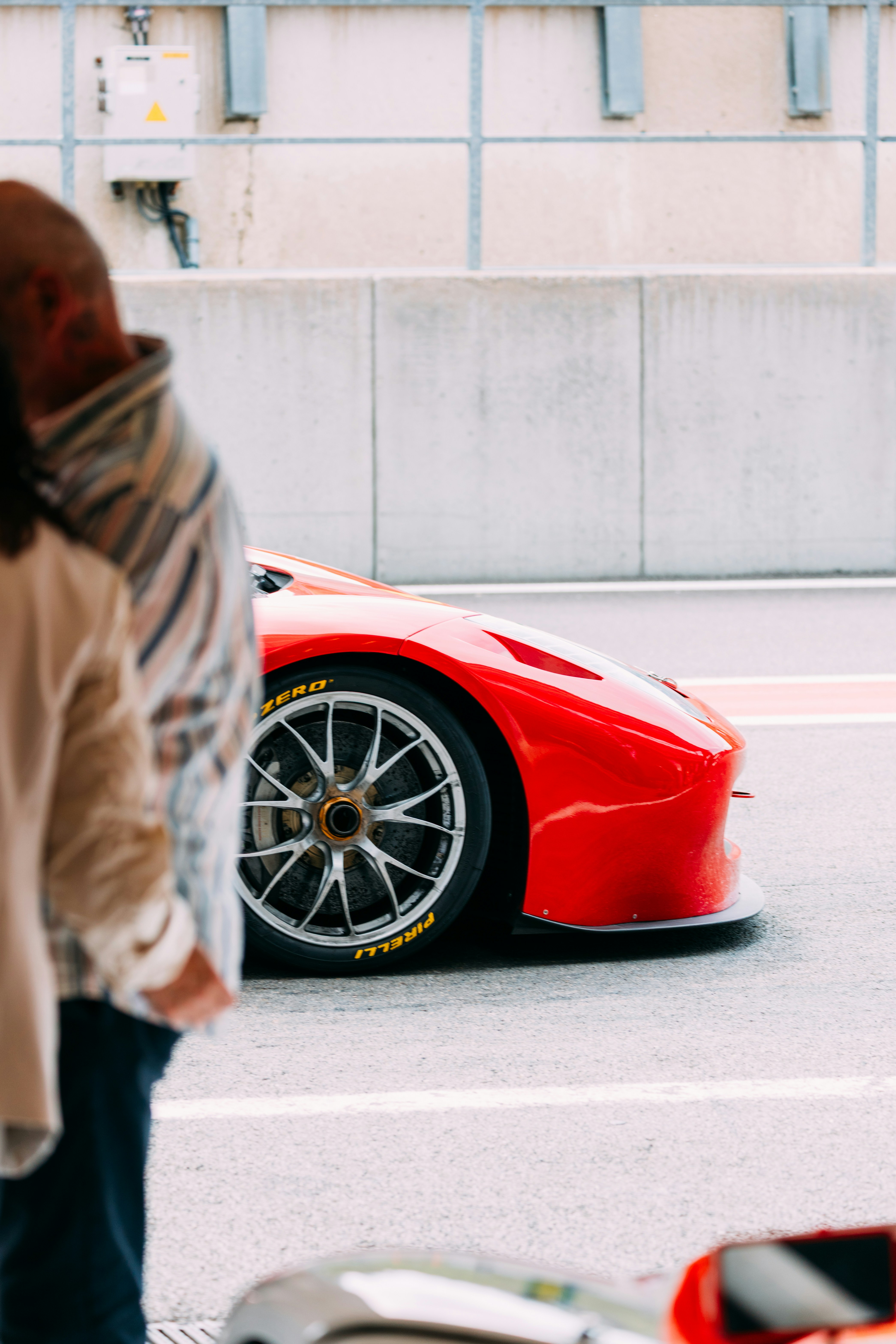 Ein roter Rennwagen parkt in der Nähe von Zuschauern.