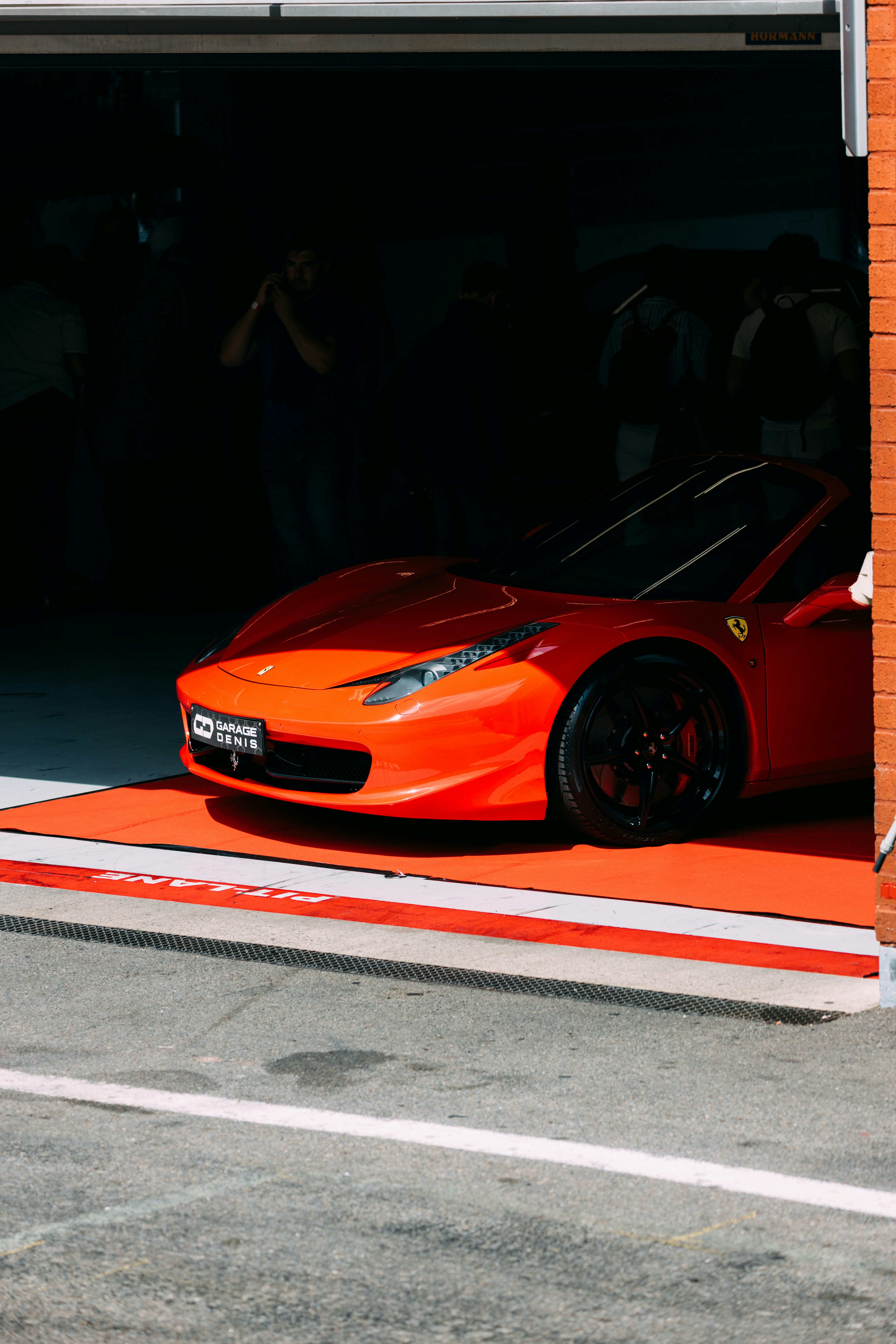 Ein roter Ferrari rollt aus einer Garage.