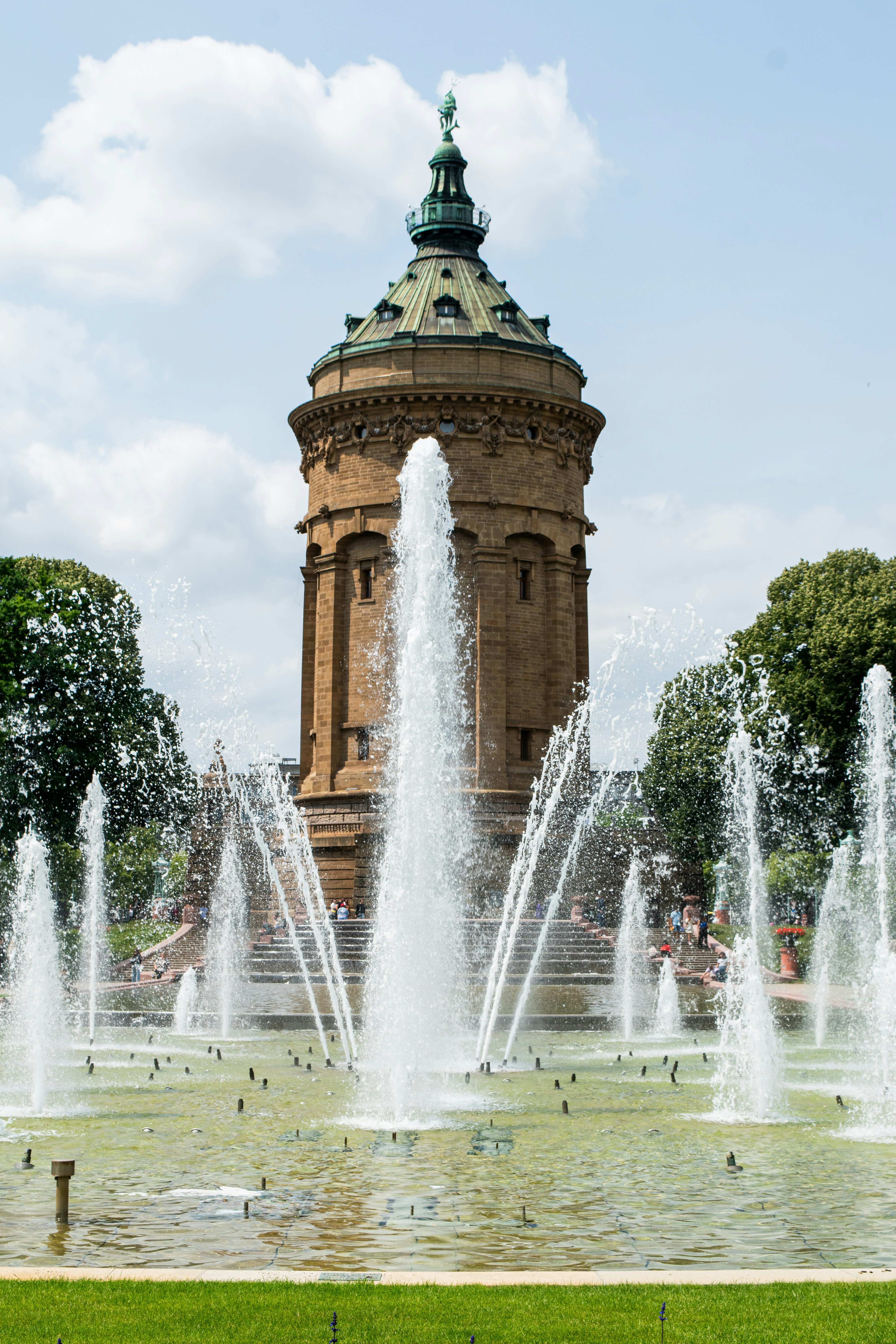 A tower stands behind dancing water fountains.