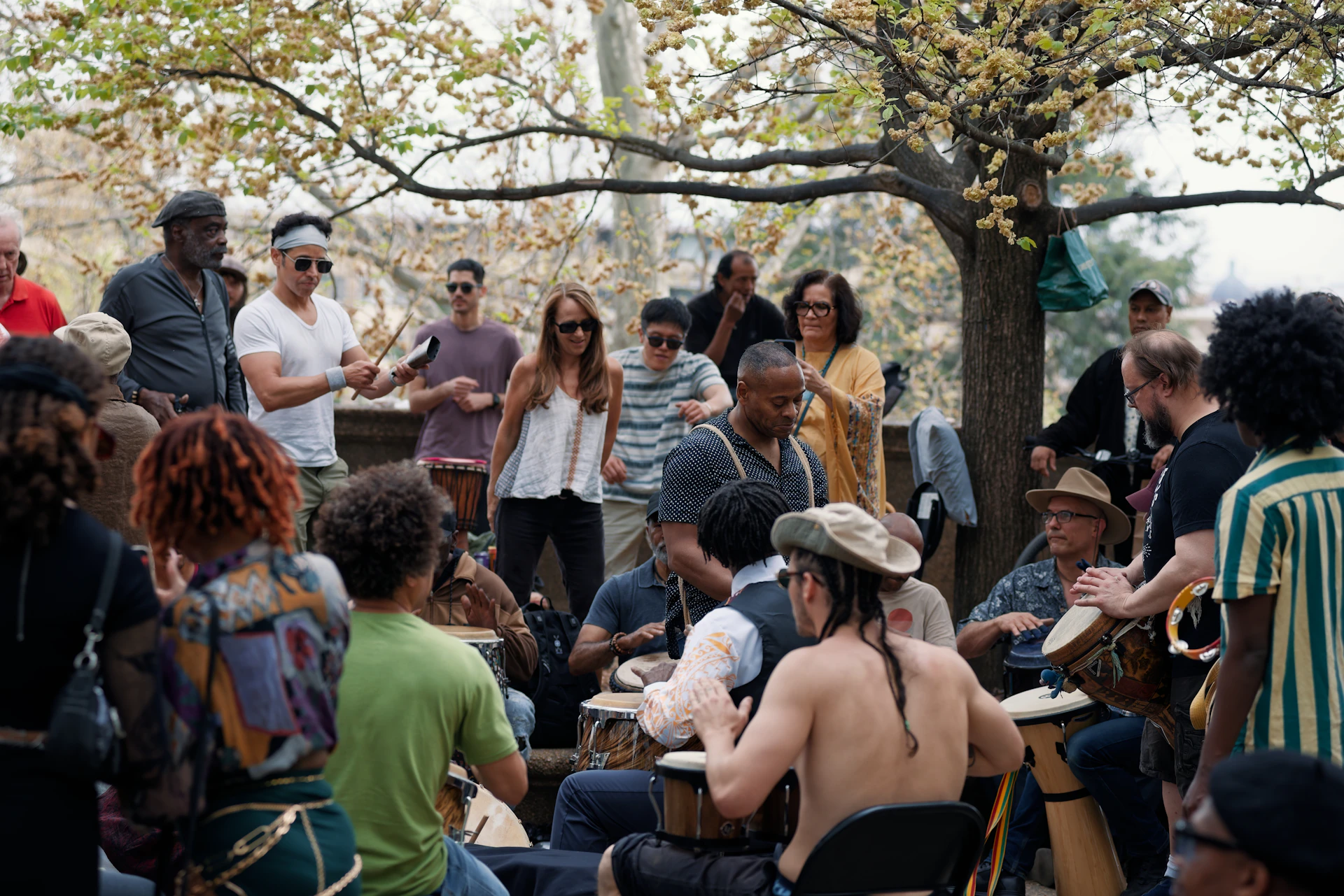 People are playing drums and dancing in a park.