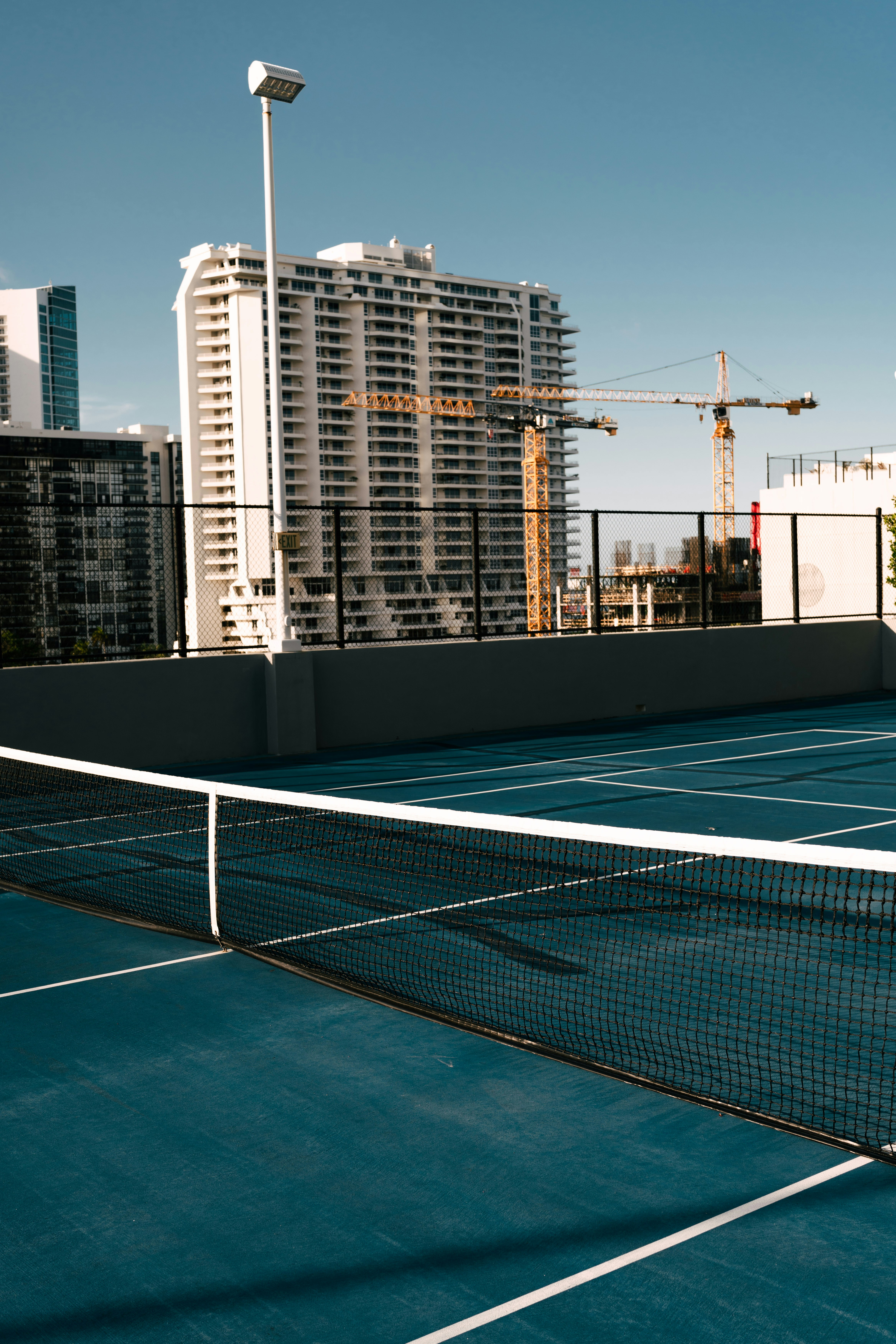 Tennis court overlooking city buildings on a sunny day.