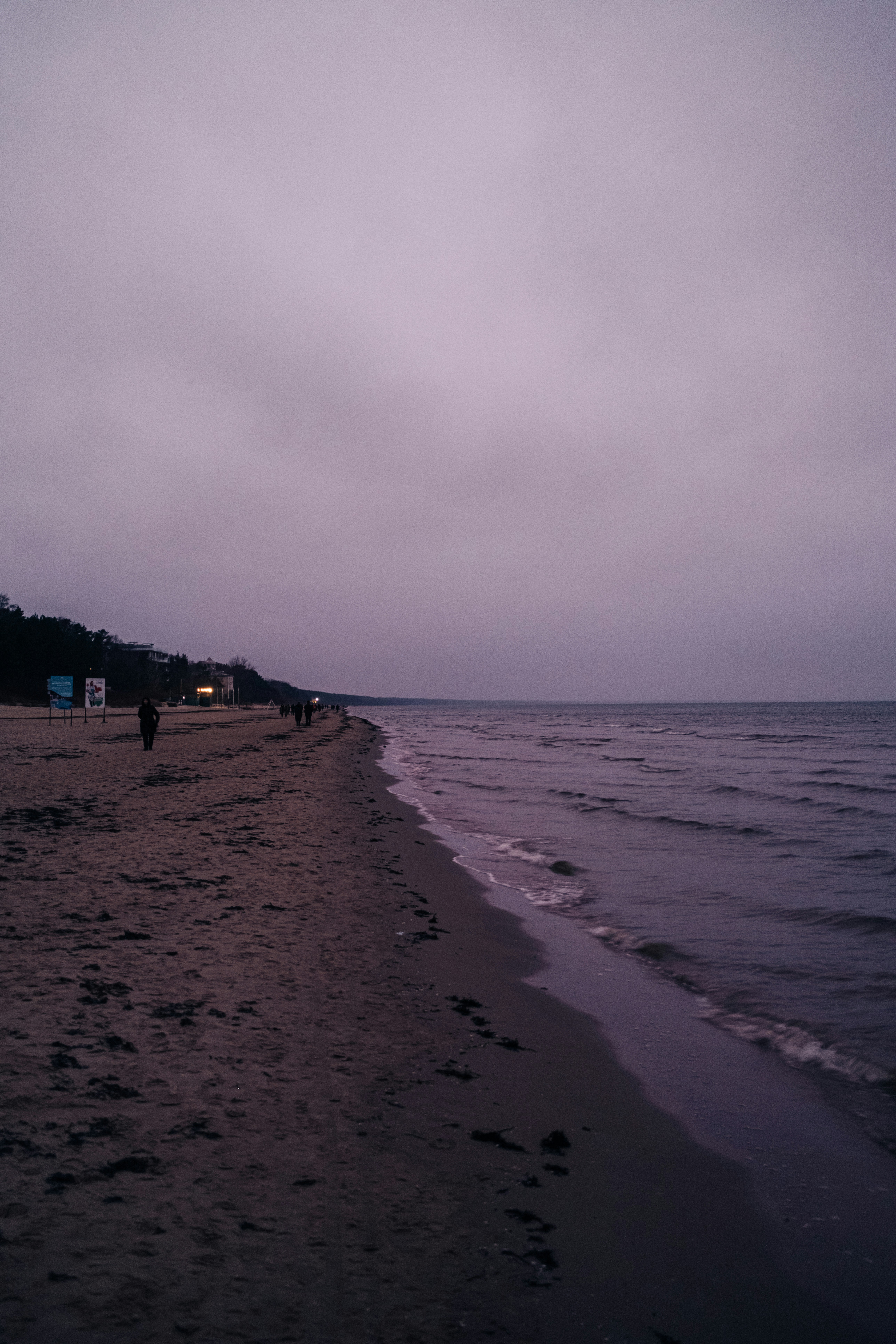 A beach stretches under a dusky, grey sky.