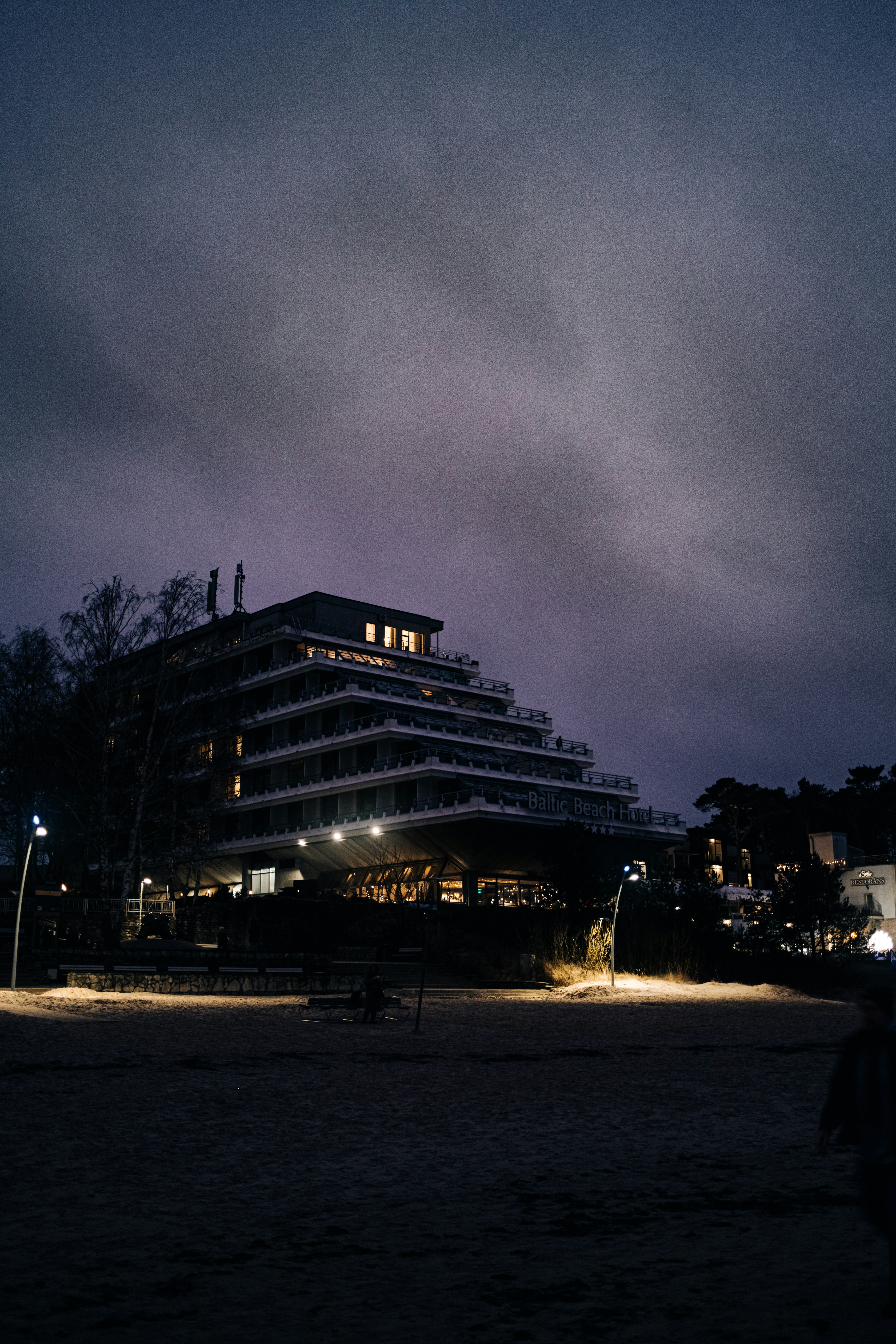 A lit hotel against a cloudy, dark evening sky.