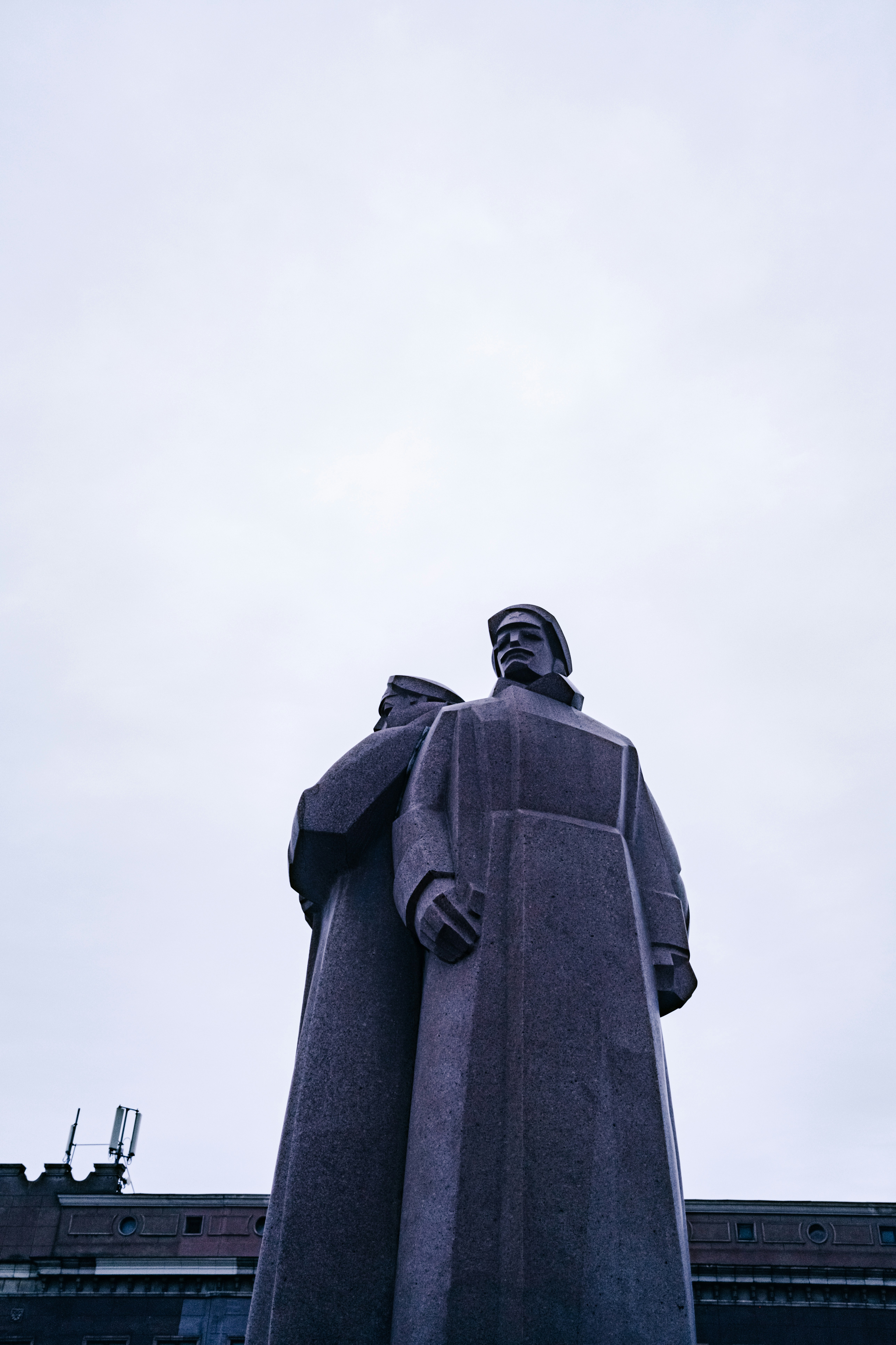 Two statues stand tall against a cloudy sky.
