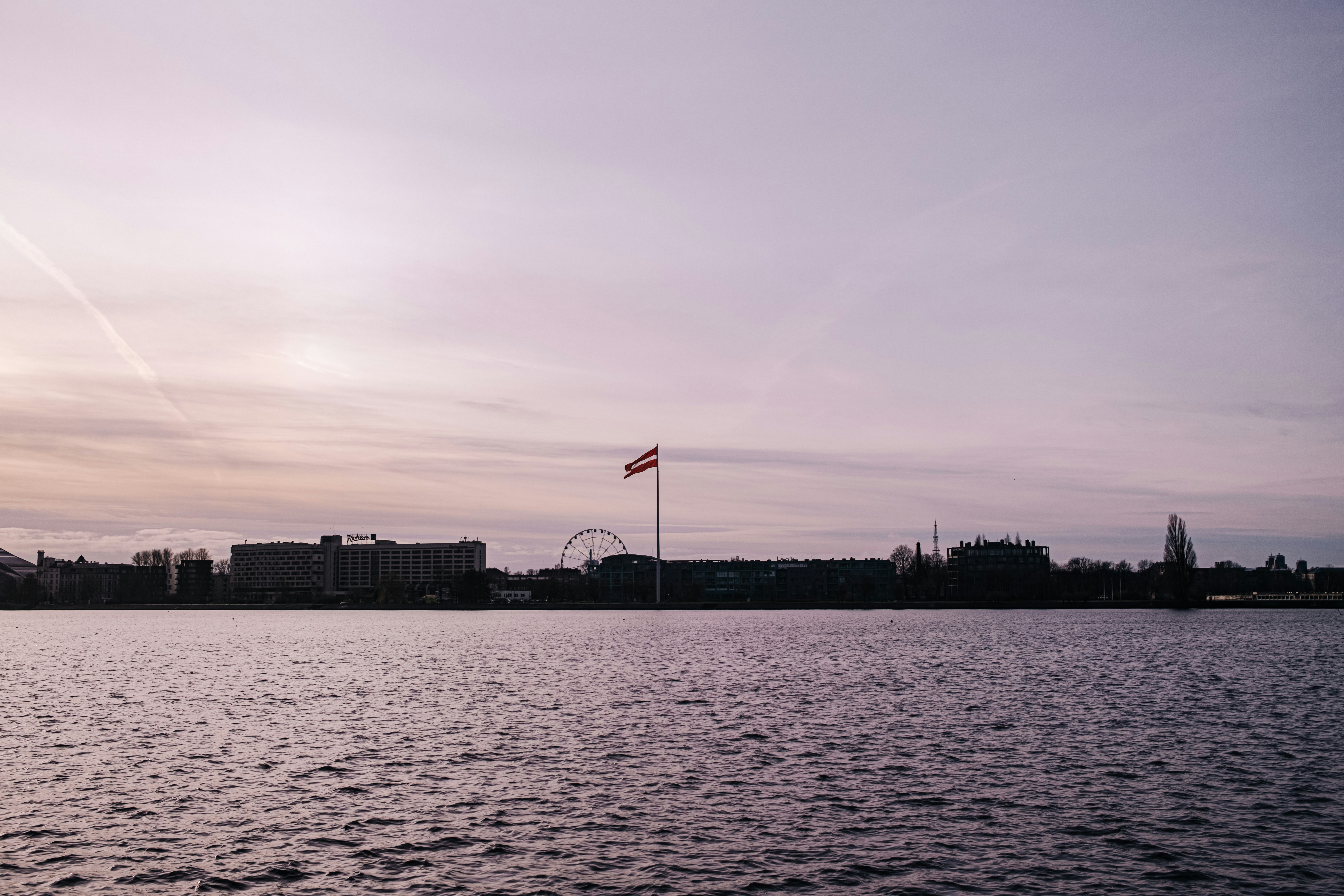 A peaceful lake with a cityscape at dusk.