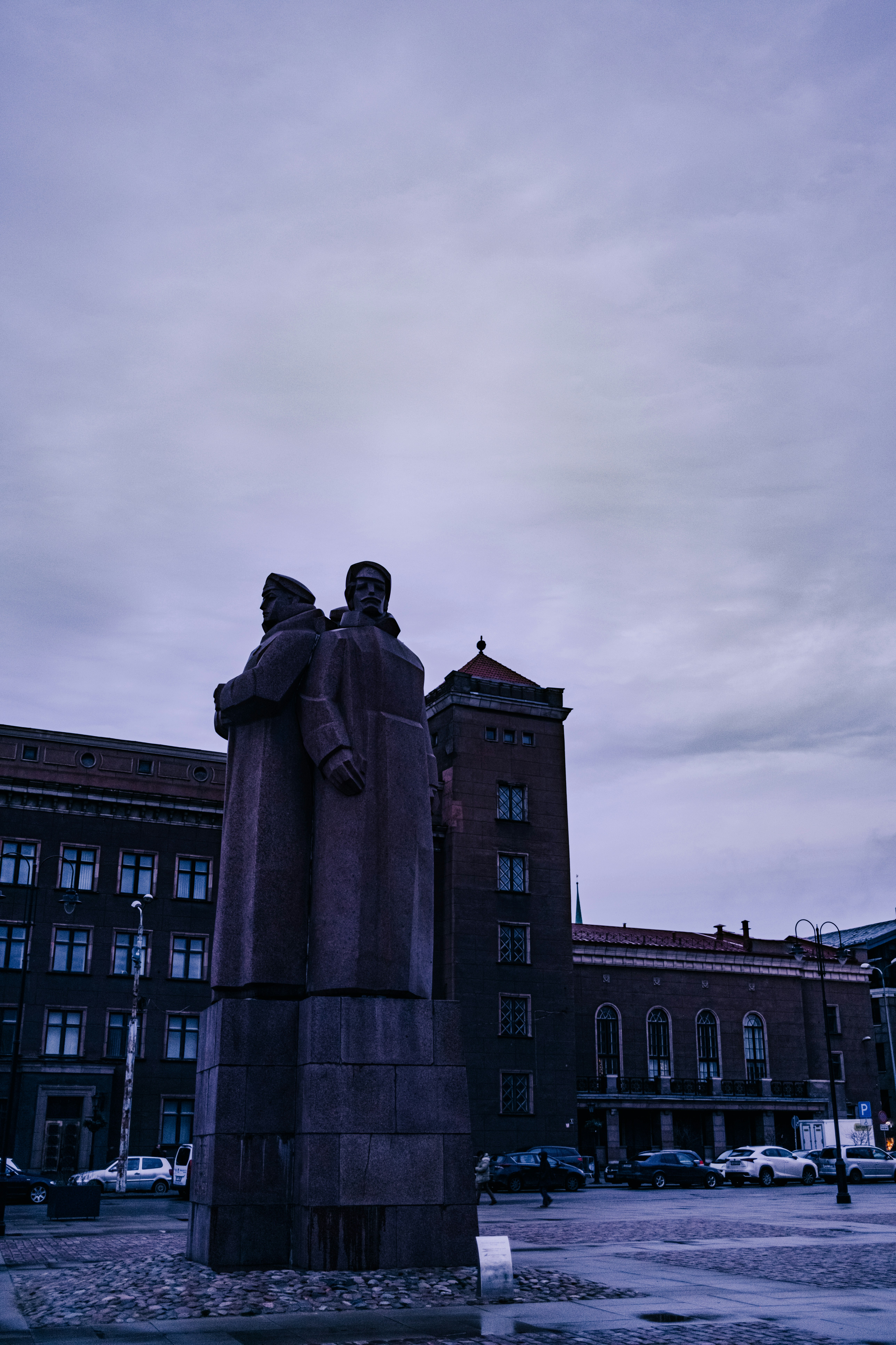 Statue of two men stands in a city square.