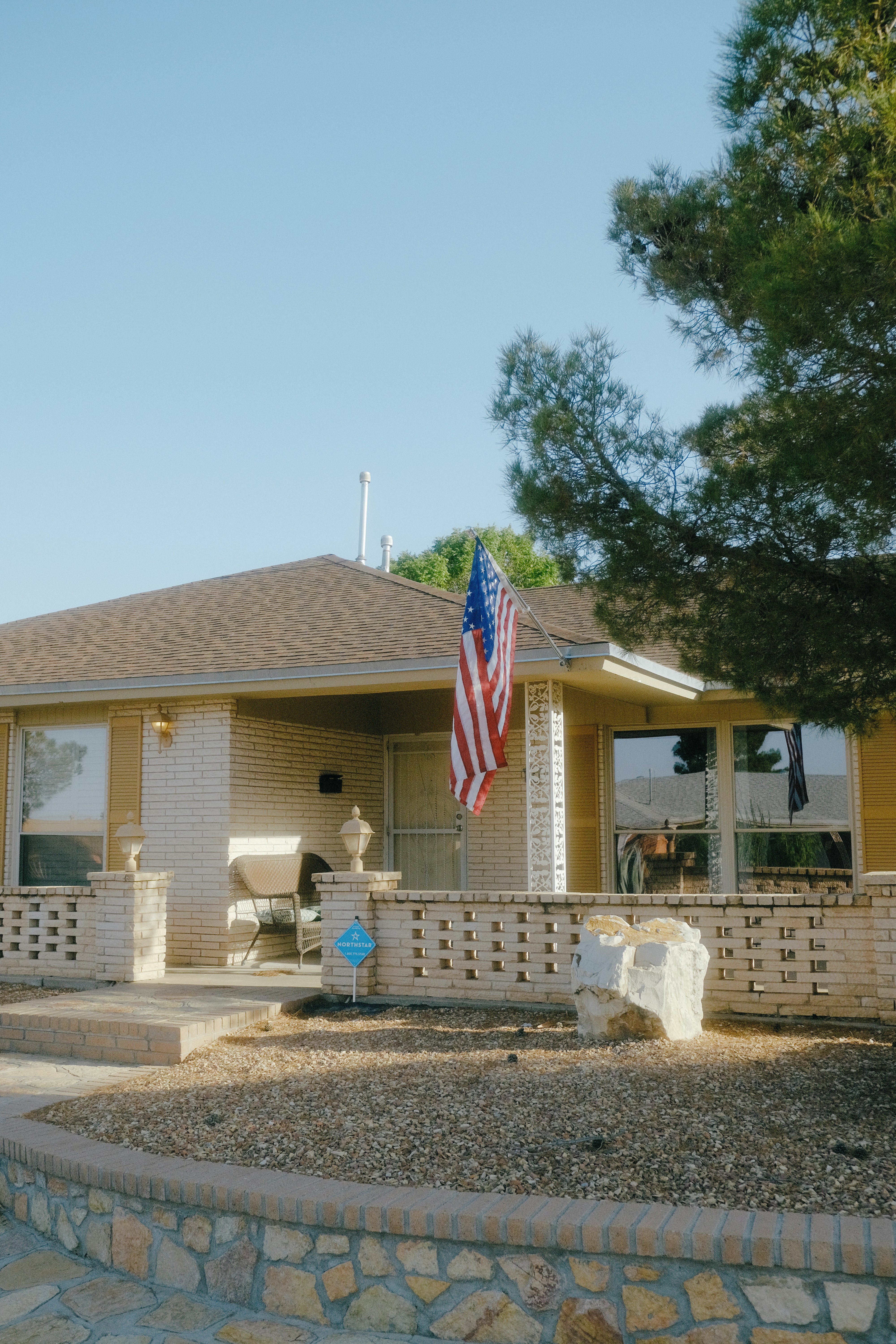American flag waves in front of a beige house
