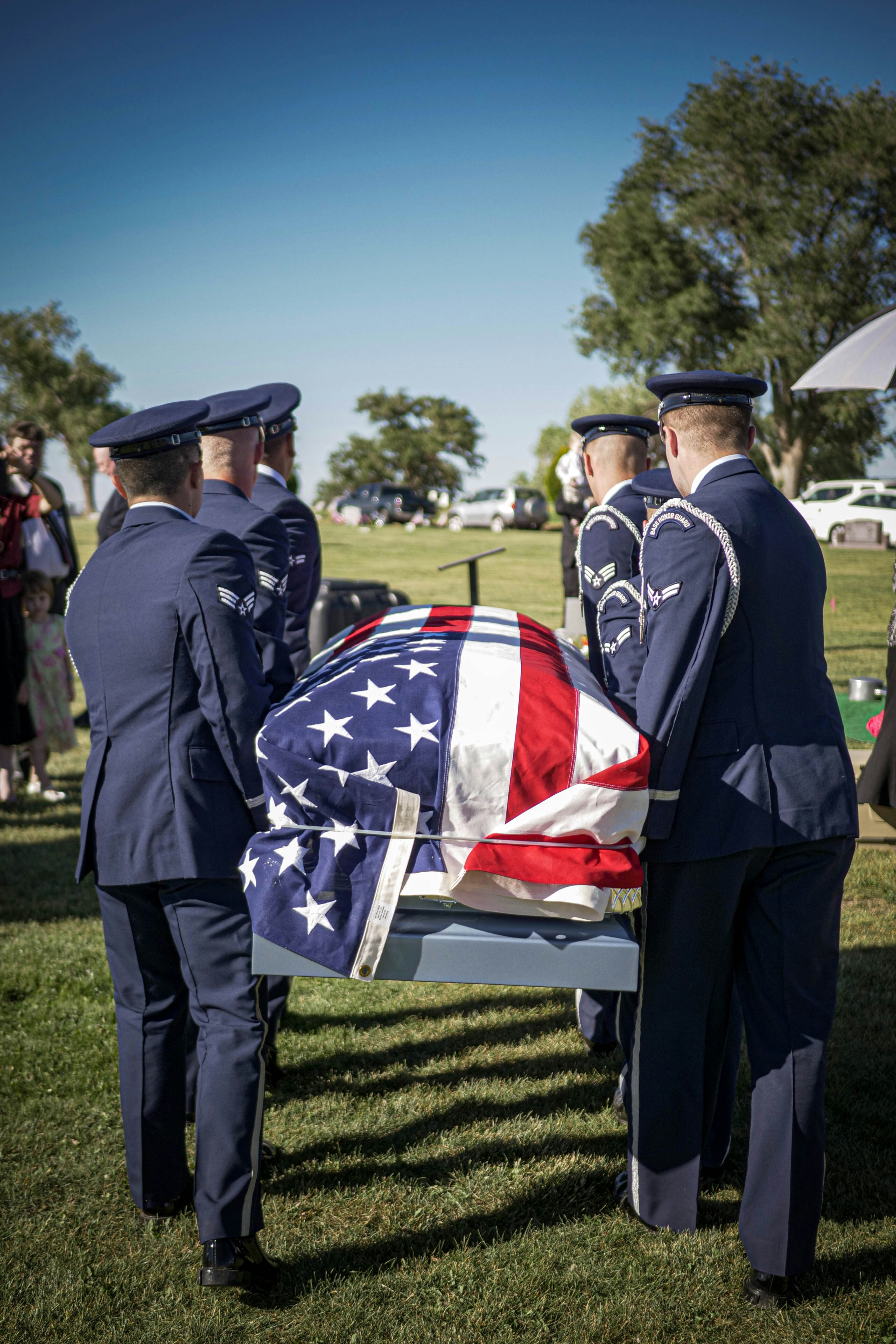 Military officers carry a casket draped in the american flag.