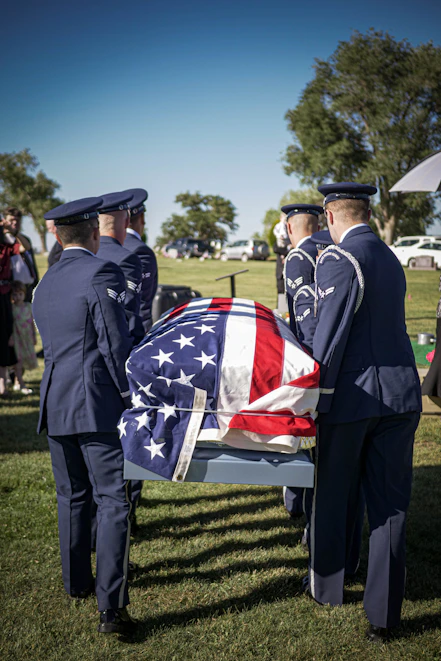Military officers carry a casket draped in the american flag.