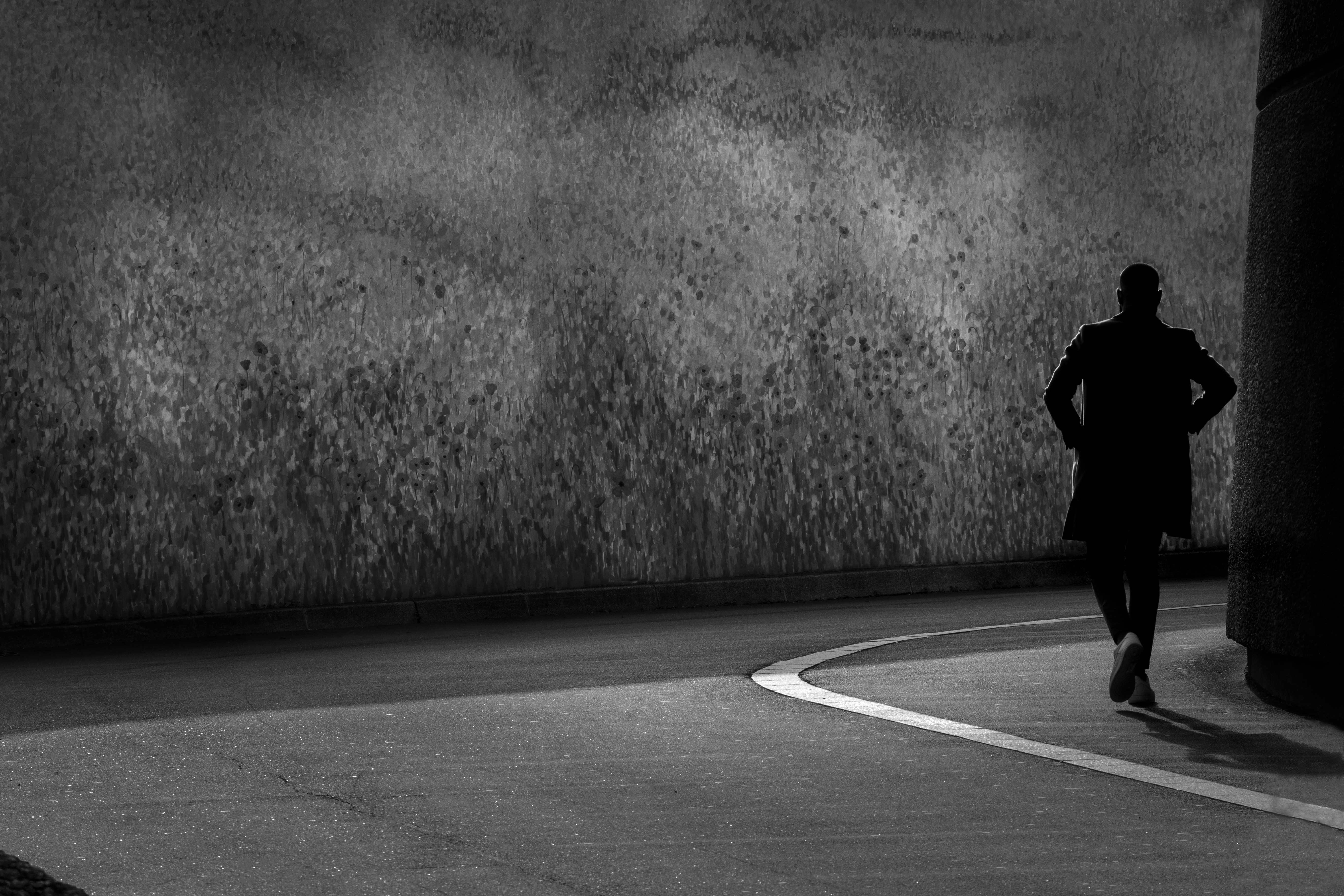 Ein Mann geht eine dunkle, schmale Straße entlang.