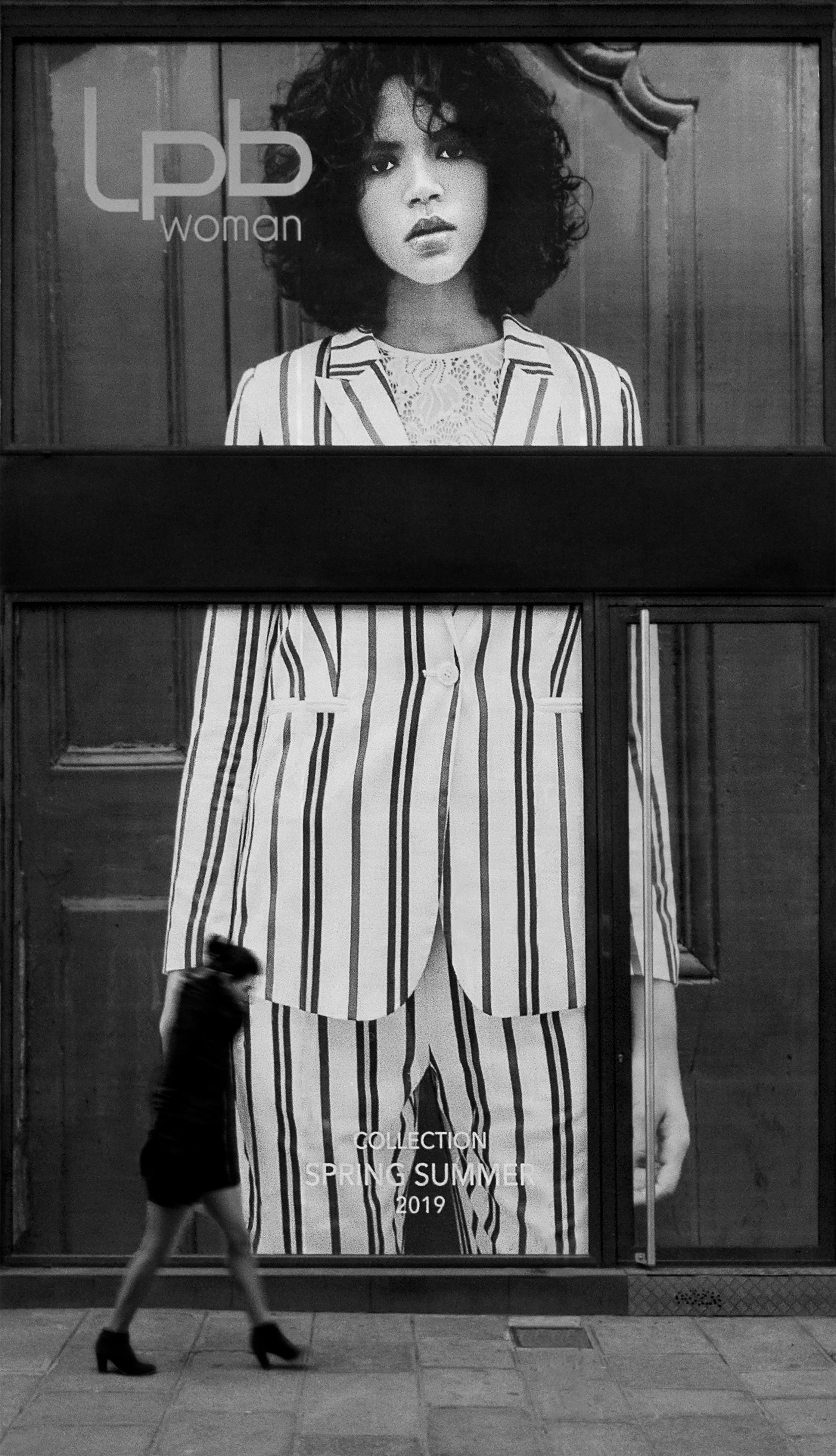 Eine Frau geht an einer Schwarz-Weiß-Werbung vorbei.