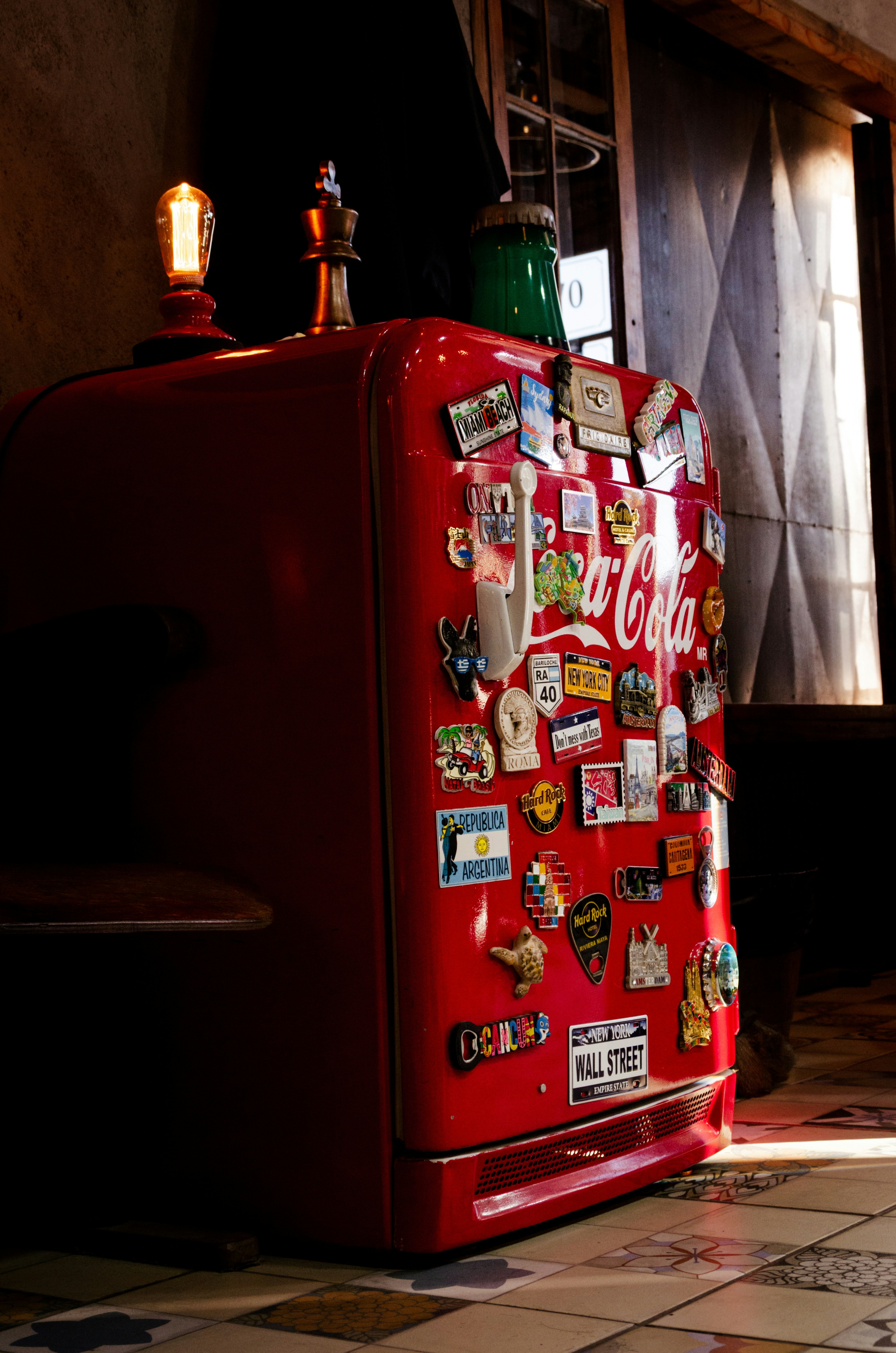Red coca-cola fridge with magnets, indoors.