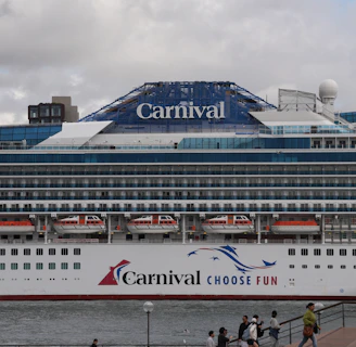 A carnival cruise ship is docked at a pier.