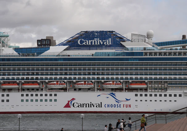 A carnival cruise ship is docked at a pier.