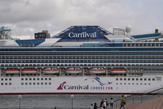 A carnival cruise ship is docked at a pier.