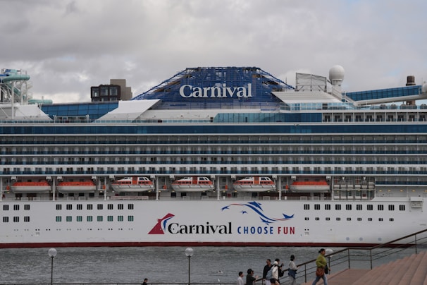 A carnival cruise ship is docked at a pier.