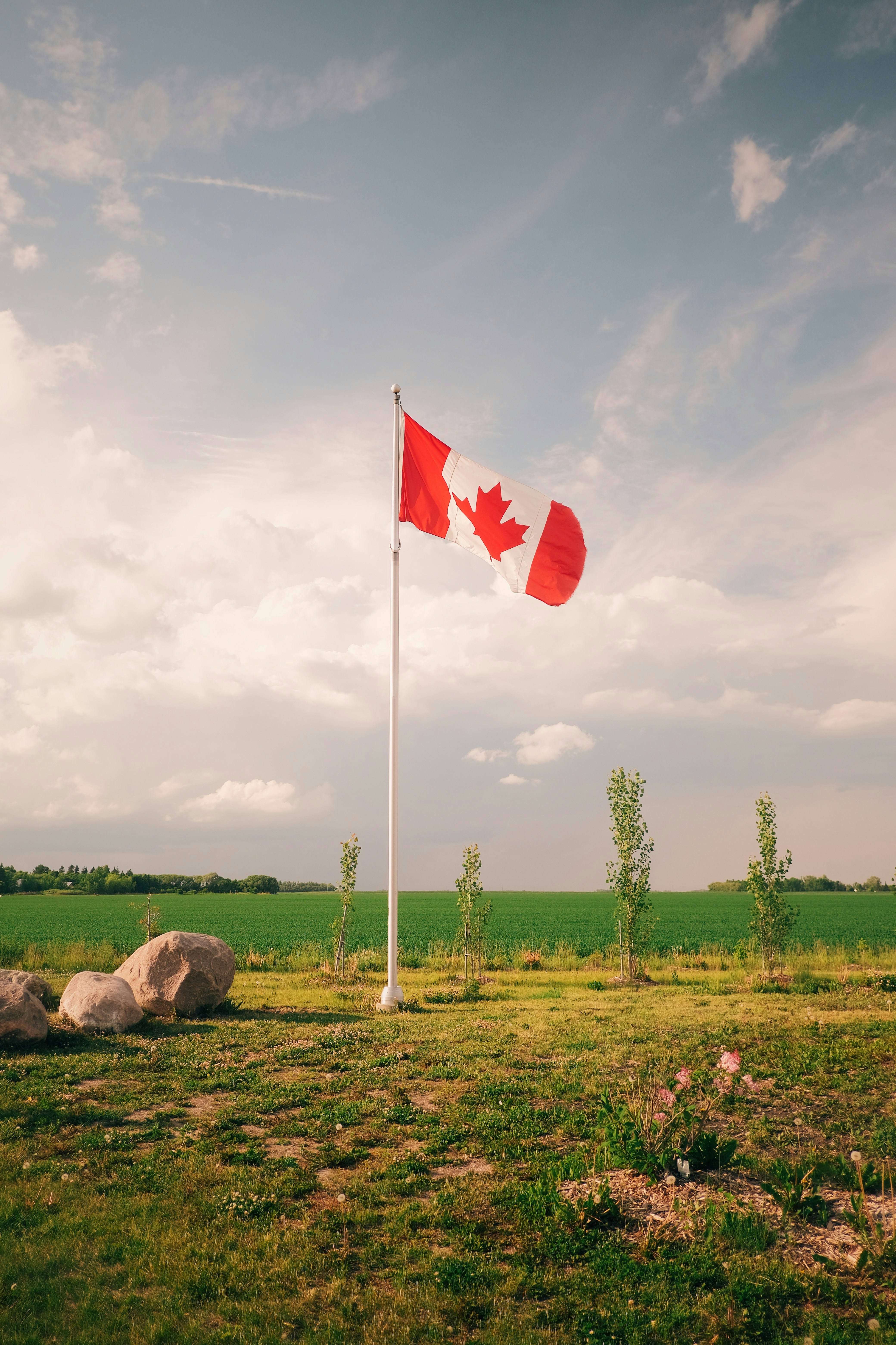 The canadian flag waves under a cloudy sky.