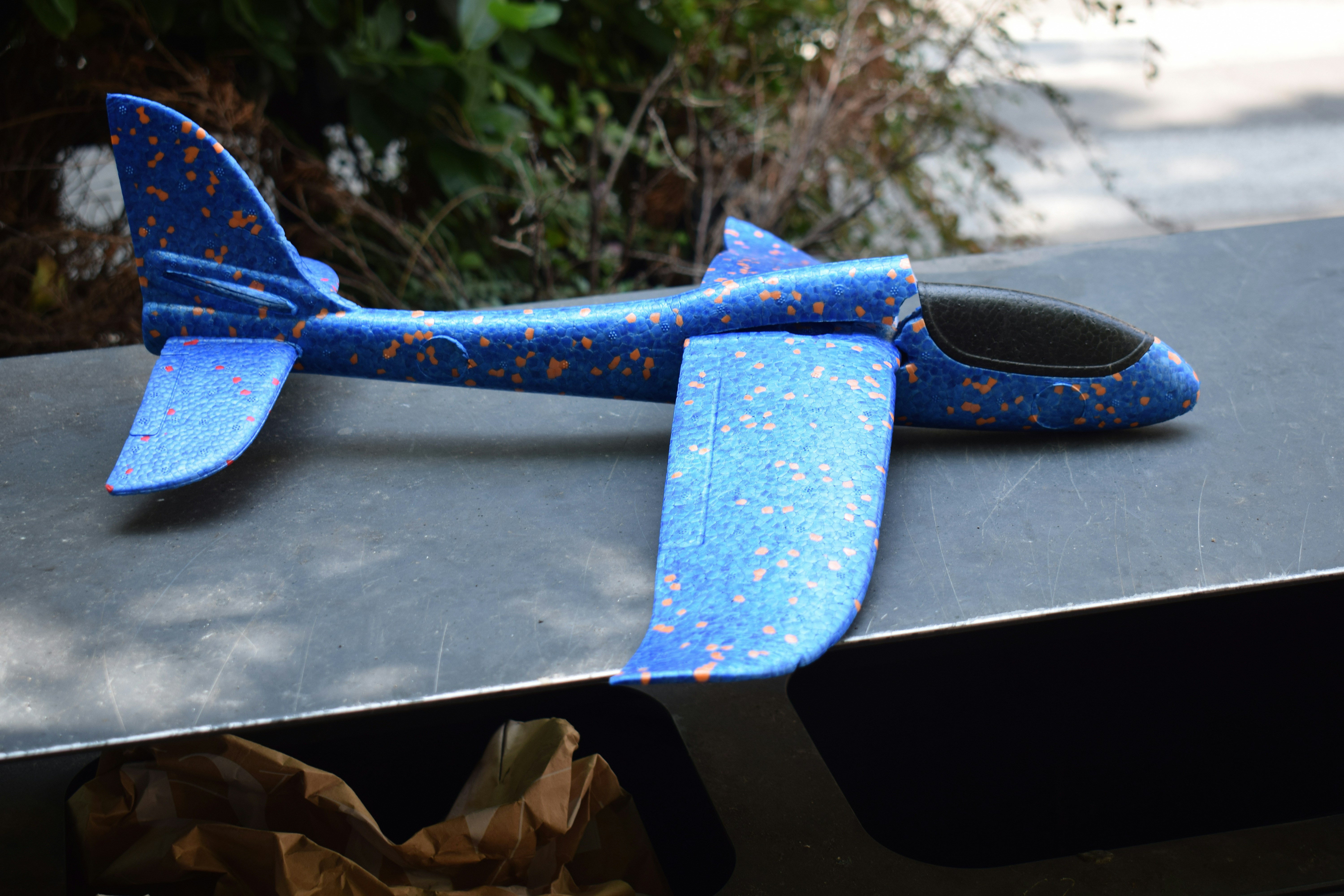 A blue toy airplane sits outside.