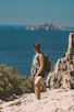 Woman hikes cliffside overlooking the ocean.