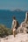 Woman hikes cliffside overlooking the ocean.