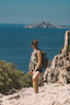 Woman hikes cliffside overlooking the ocean.