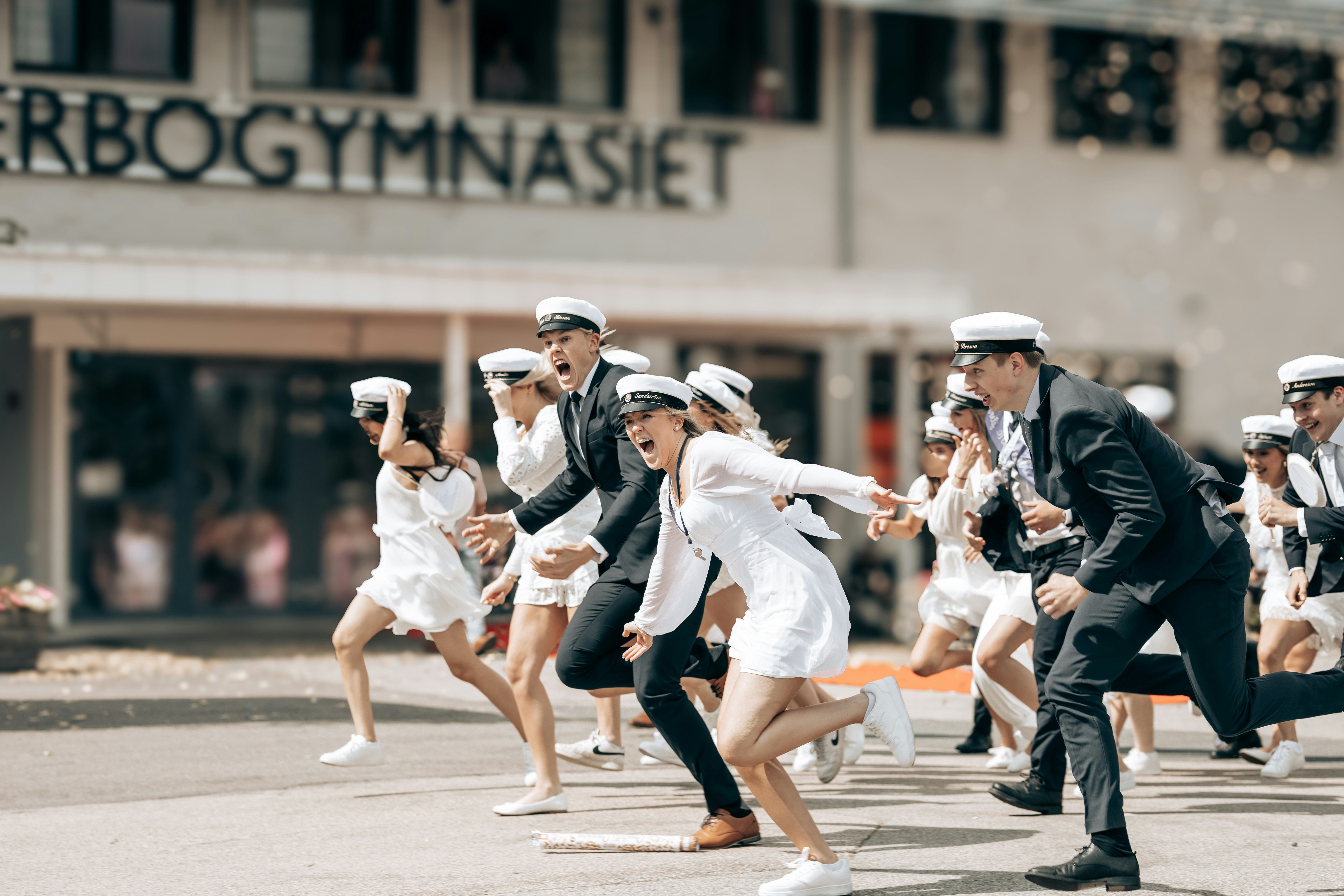 Graduating students cheerfully run from school.