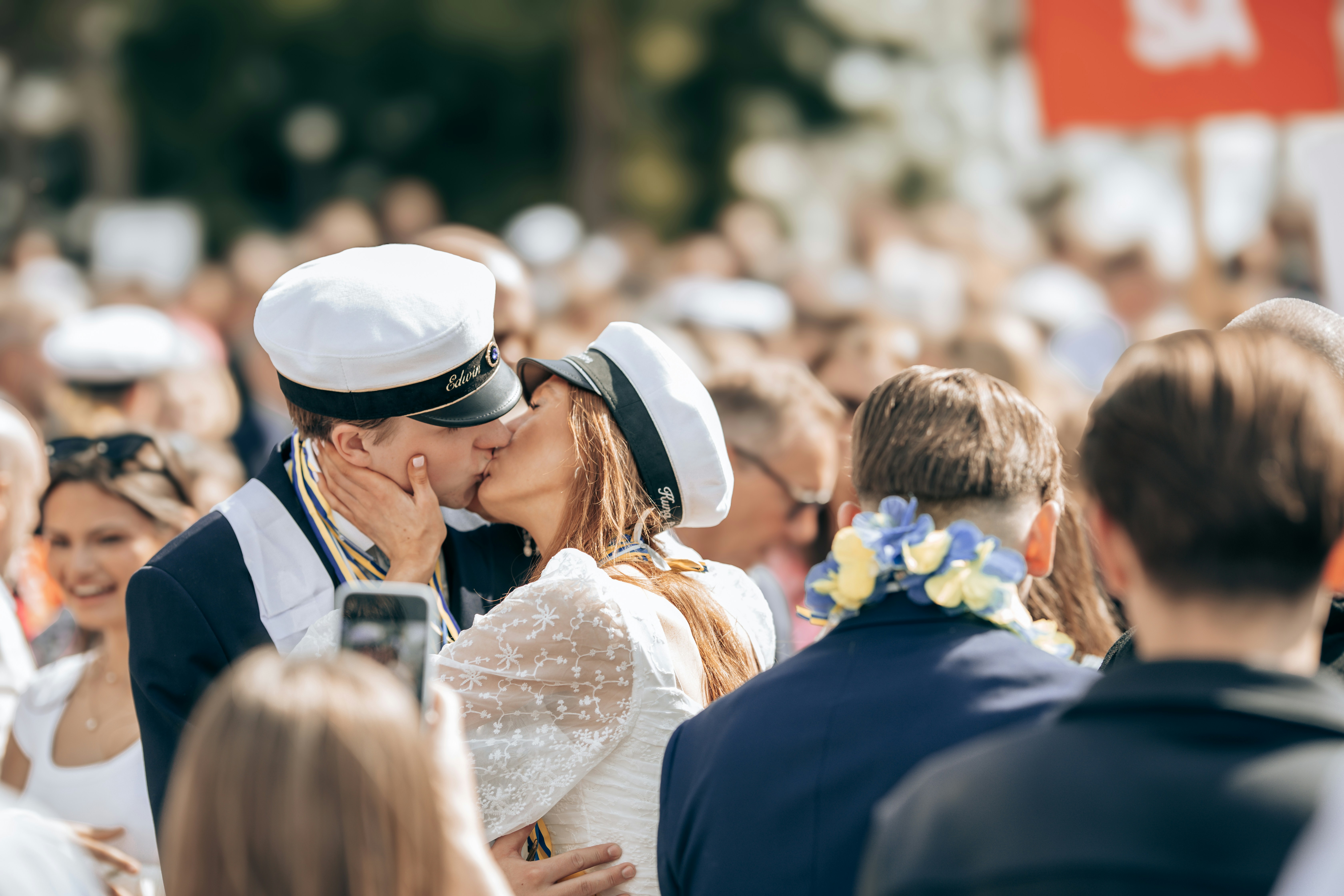A couple shares a kiss in a crowd.