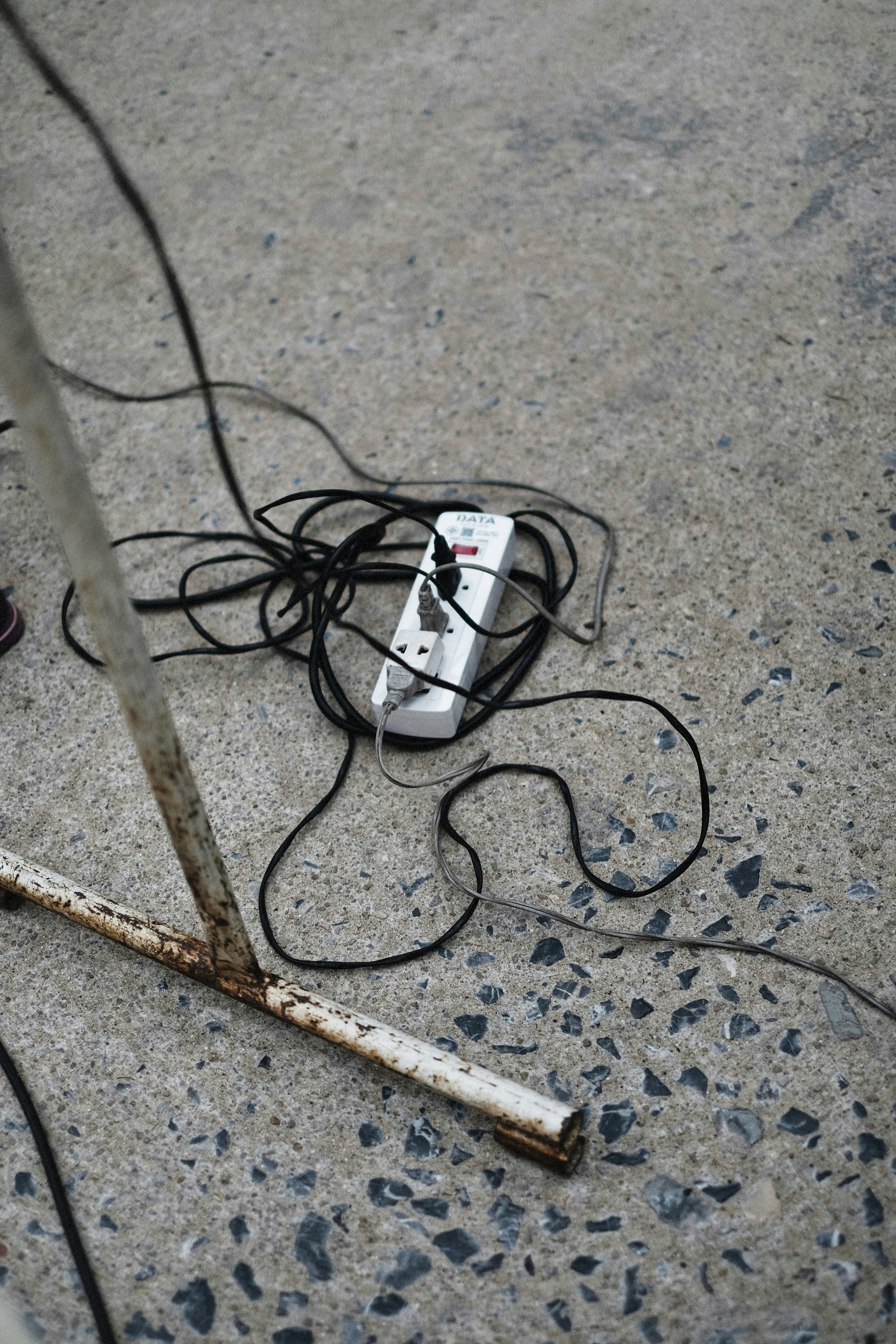 Tangled wires and a power strip on concrete.