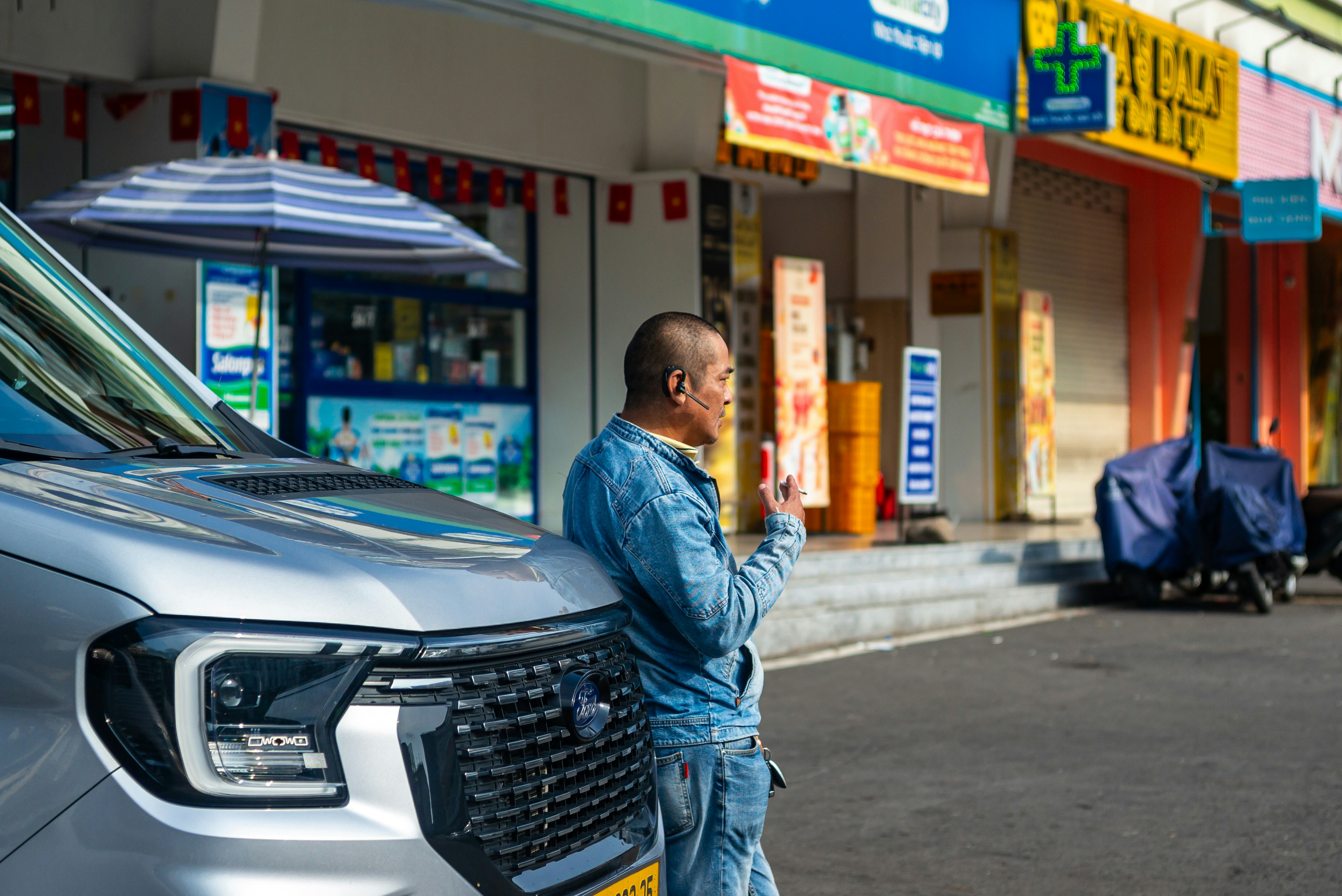 Customer inspecting a used electric car at a dealership with charging stations in the background