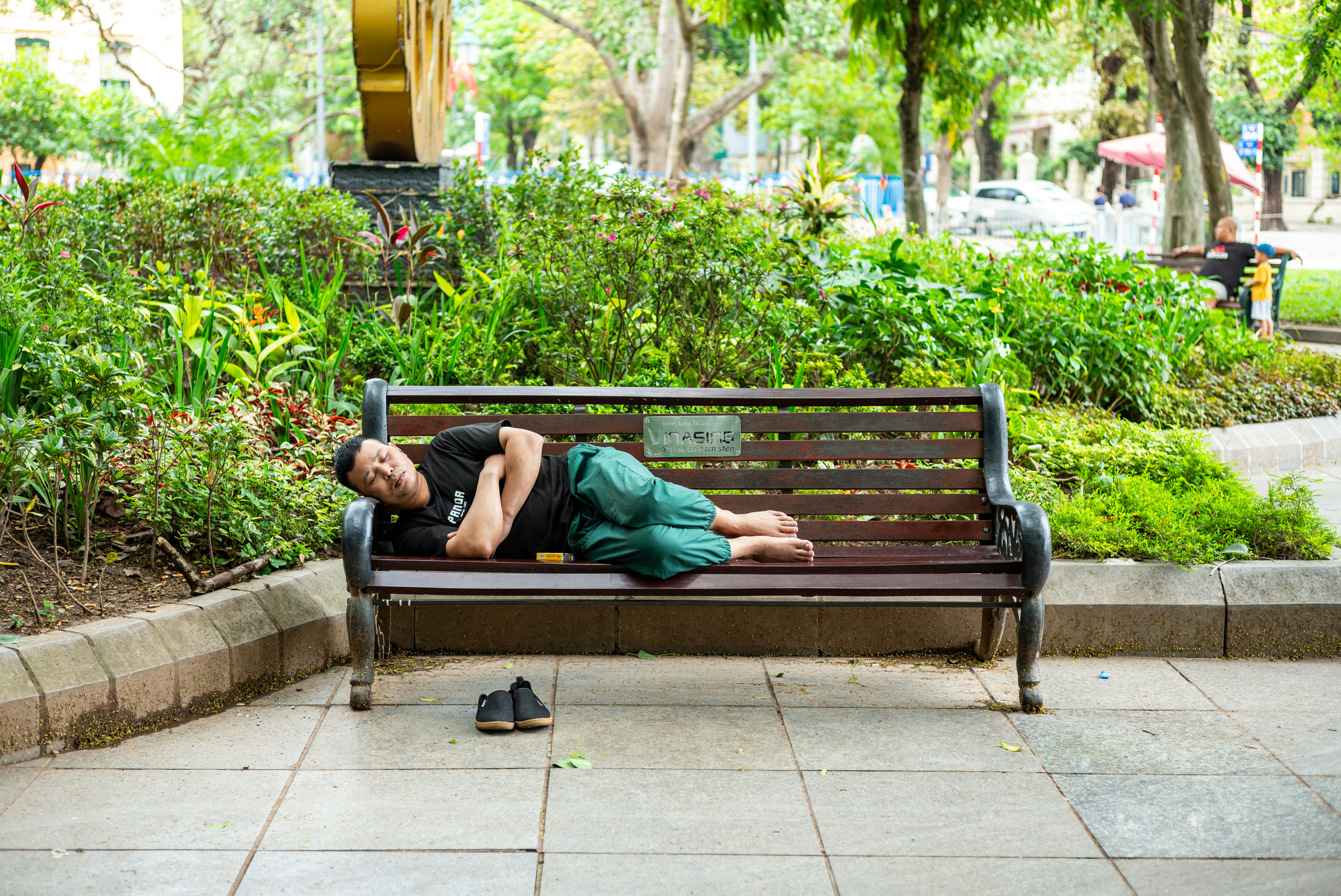 A man sleeps on a bench outdoors.
