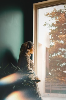 A woman looks out a window in traditional attire.