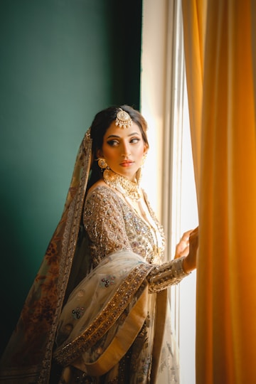 A bride in a gown gazes out the window.