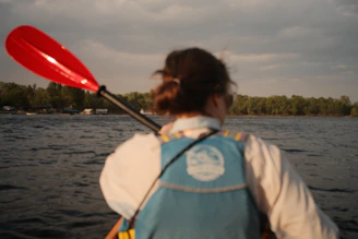 Kayaker paddles through the water under a cloudy sky.