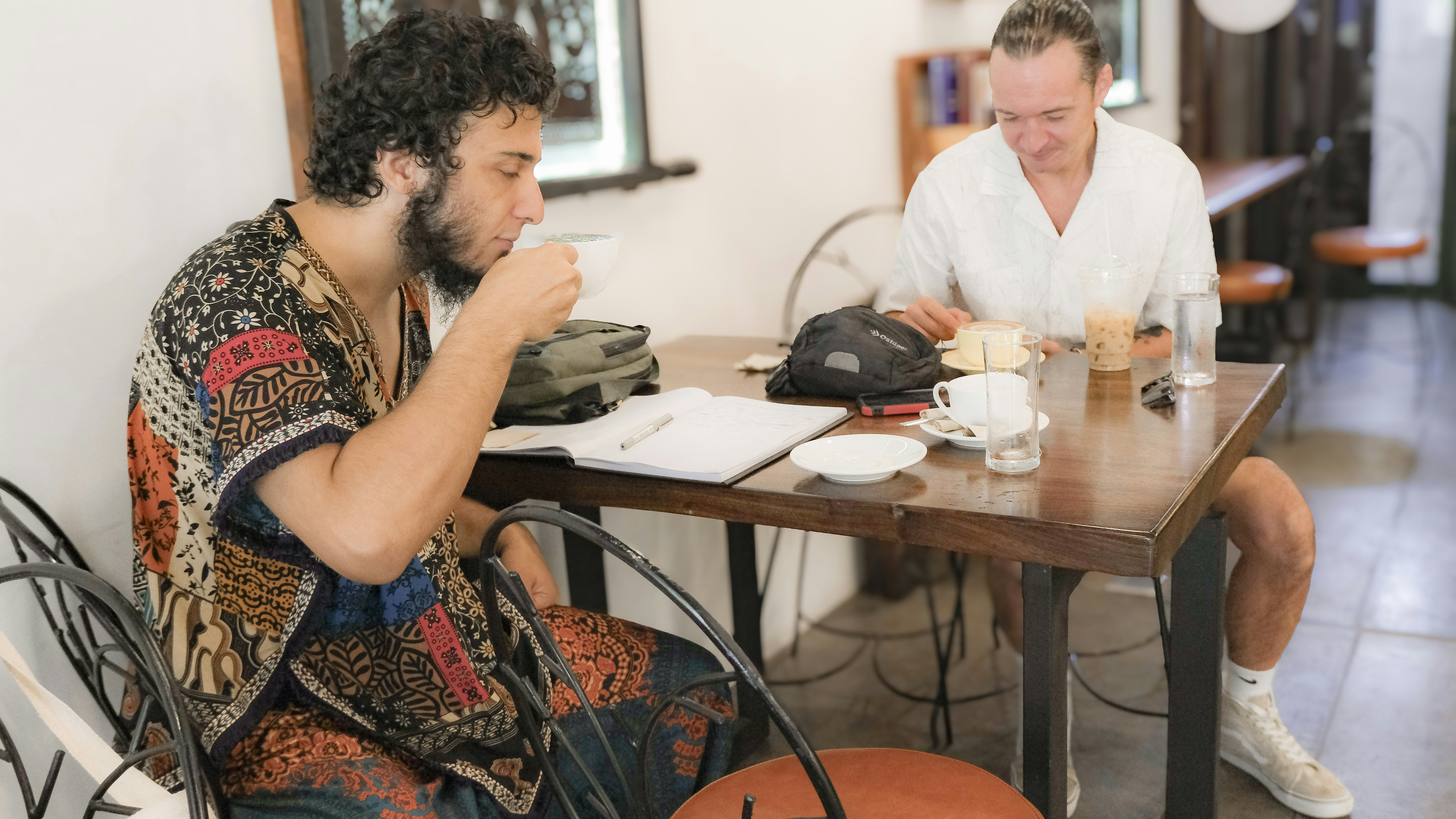 Two men enjoy coffee and pastries at a cafe.