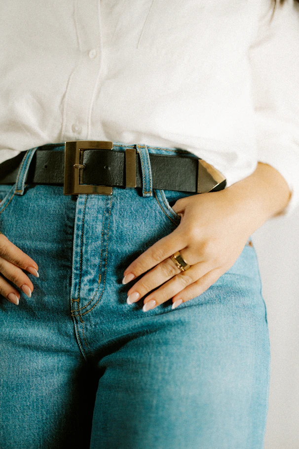 Person wears a belt and jeans with hand in the pocket.