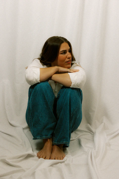 Woman huddles with arms crossed and looks away.
