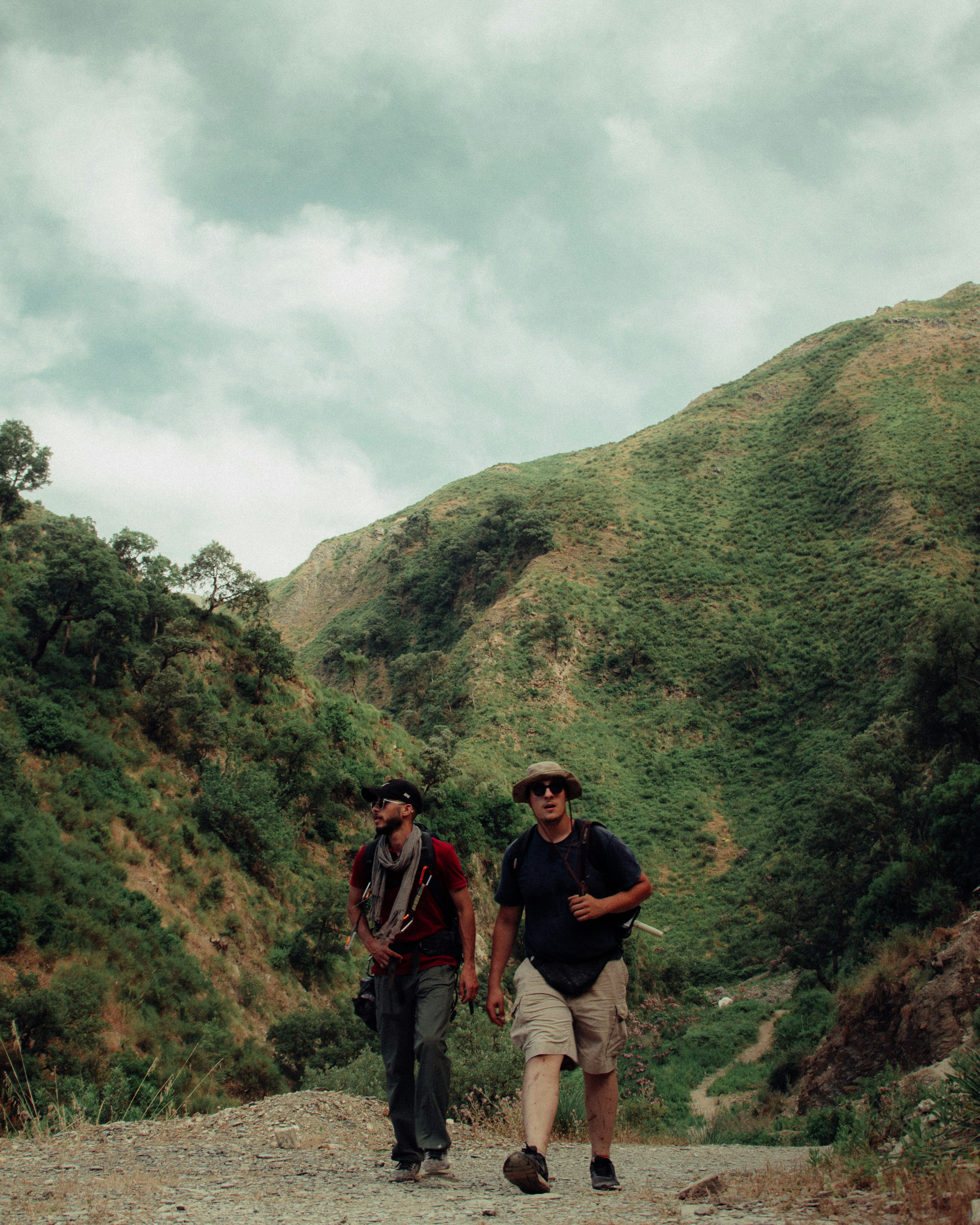 Zwei Männer wandern durch ein bergiges Gebiet.