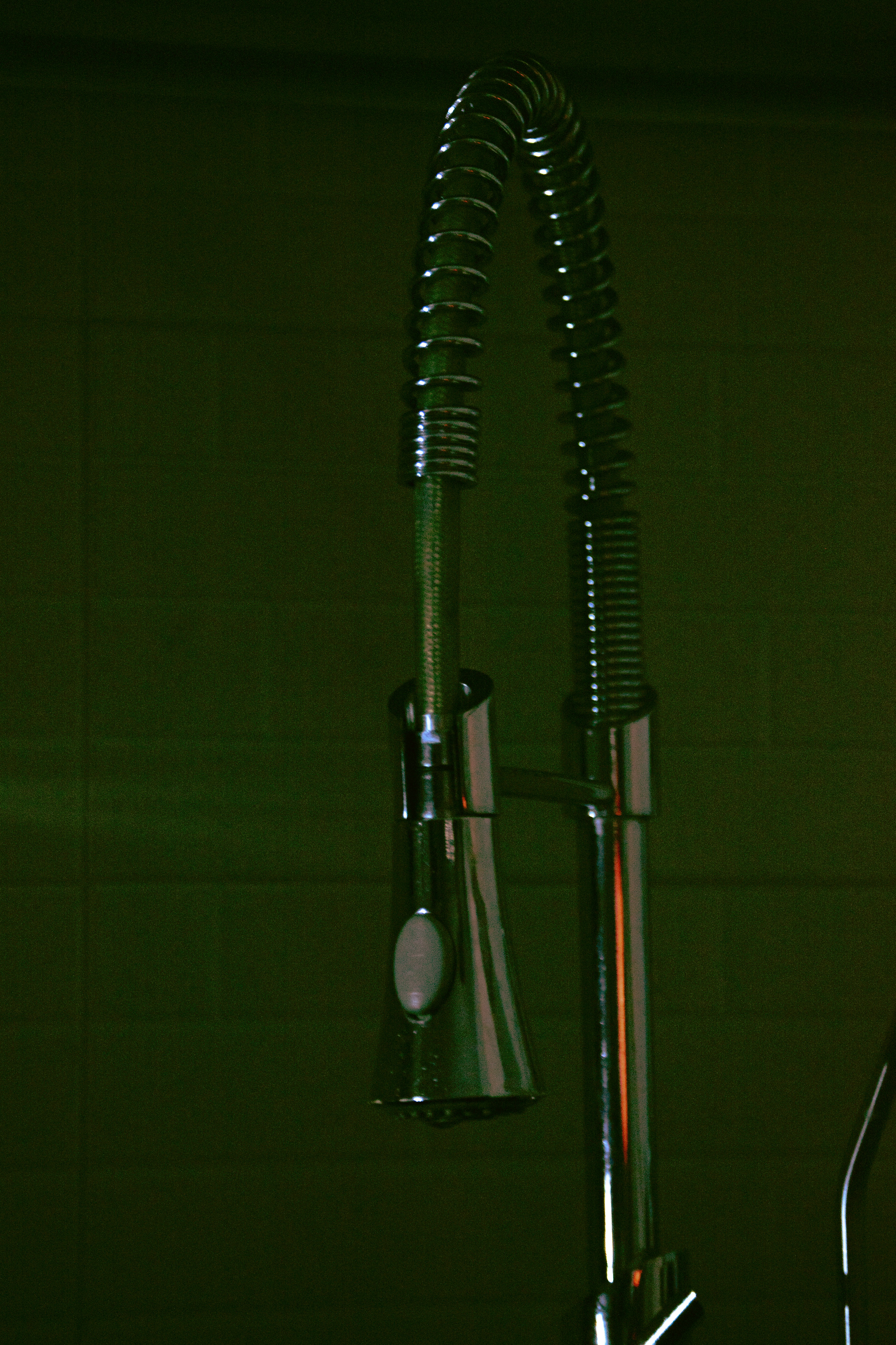 A modern kitchen faucet against a green background.