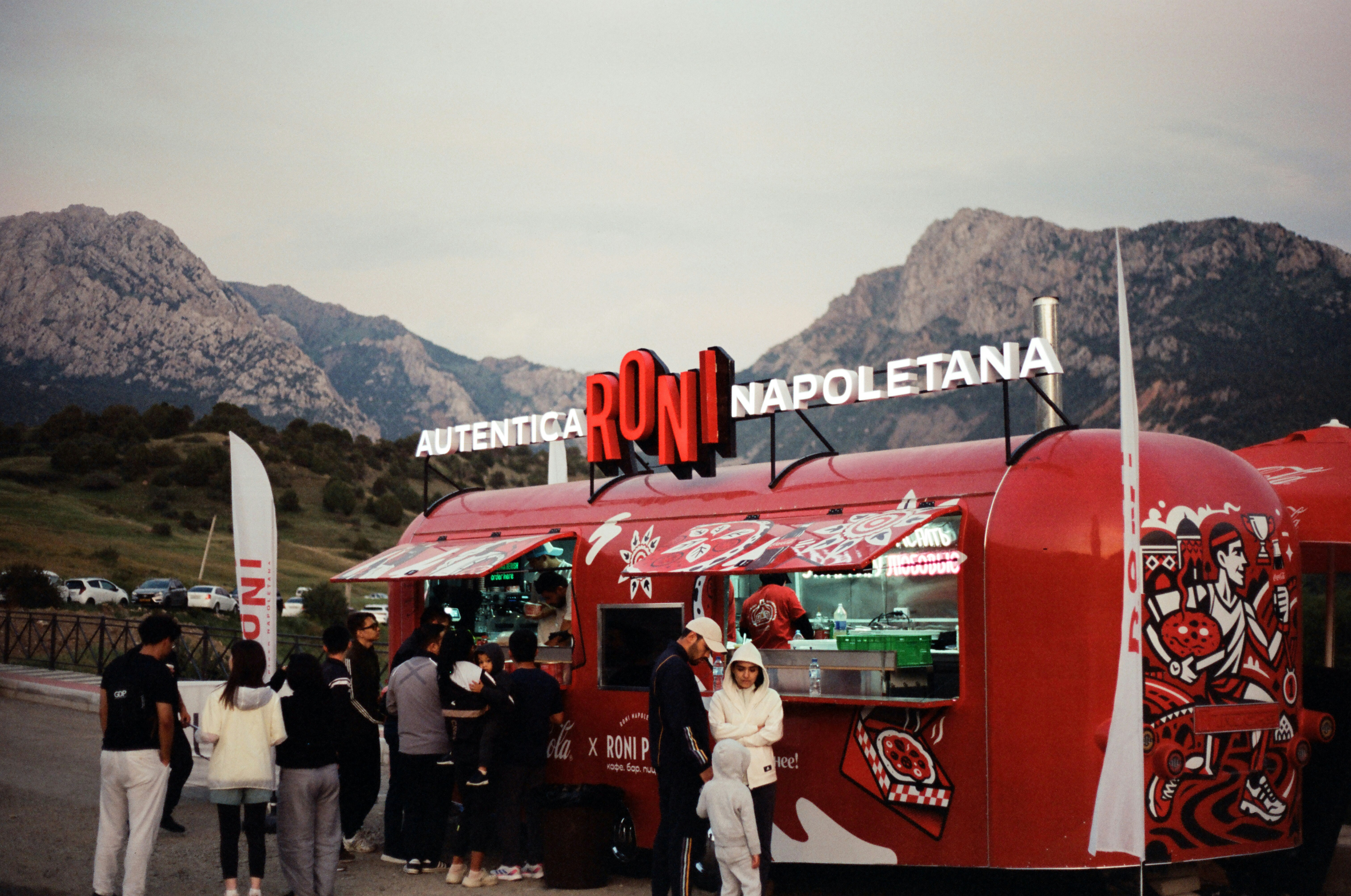 Menschen versammeln sich um einen roten Foodtruck in der Nähe von Bergen.