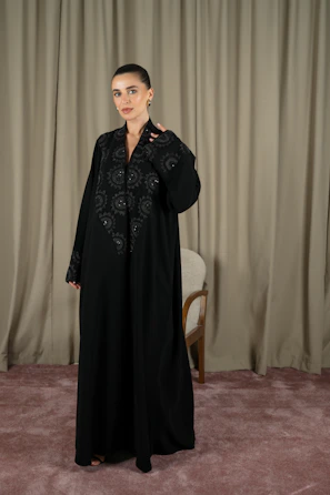 A woman models a black abaya dress.