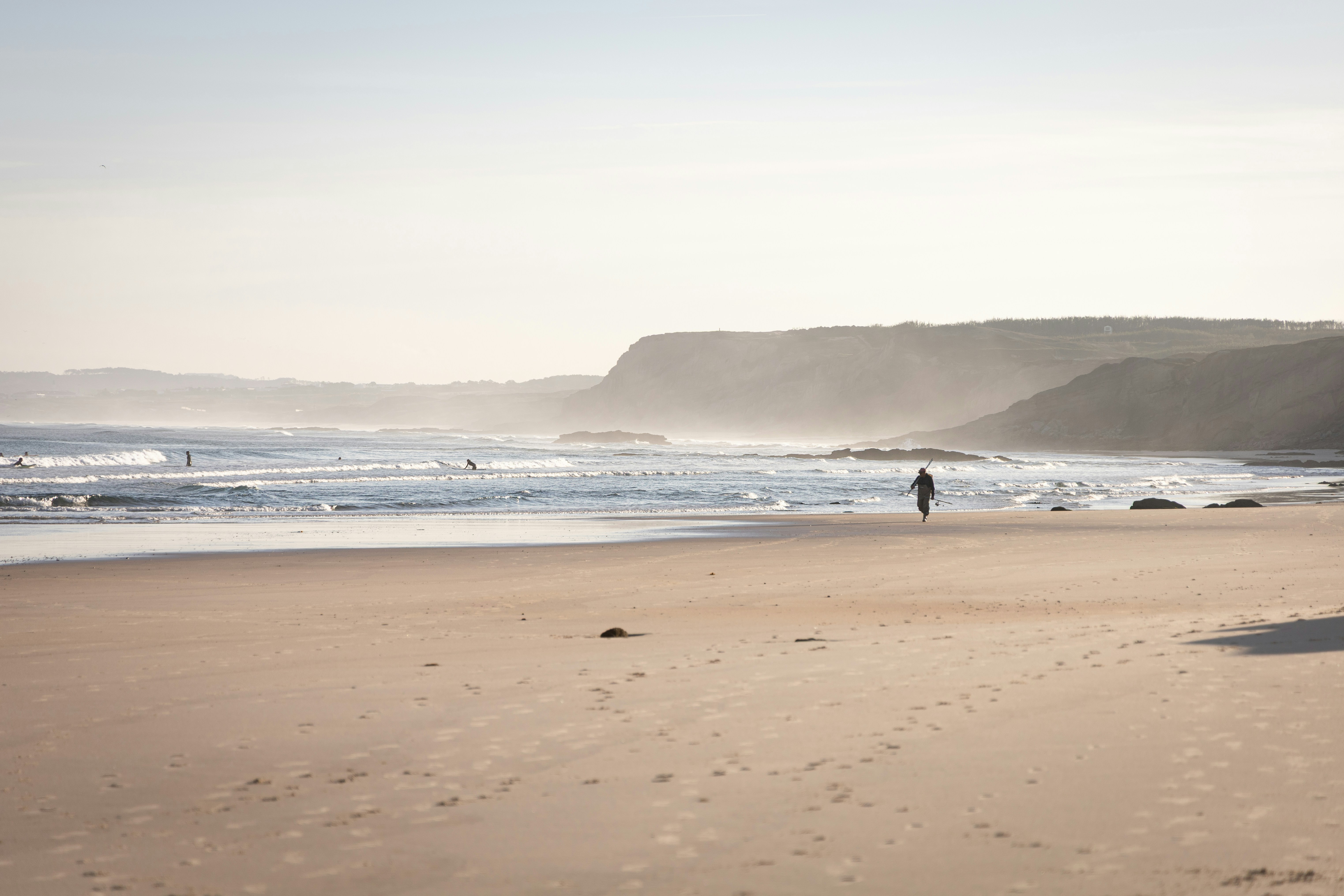 A person walks on a sunny, sandy beach.