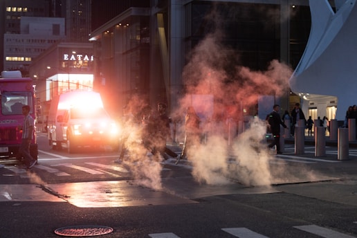 Steam rises from a city street at night.