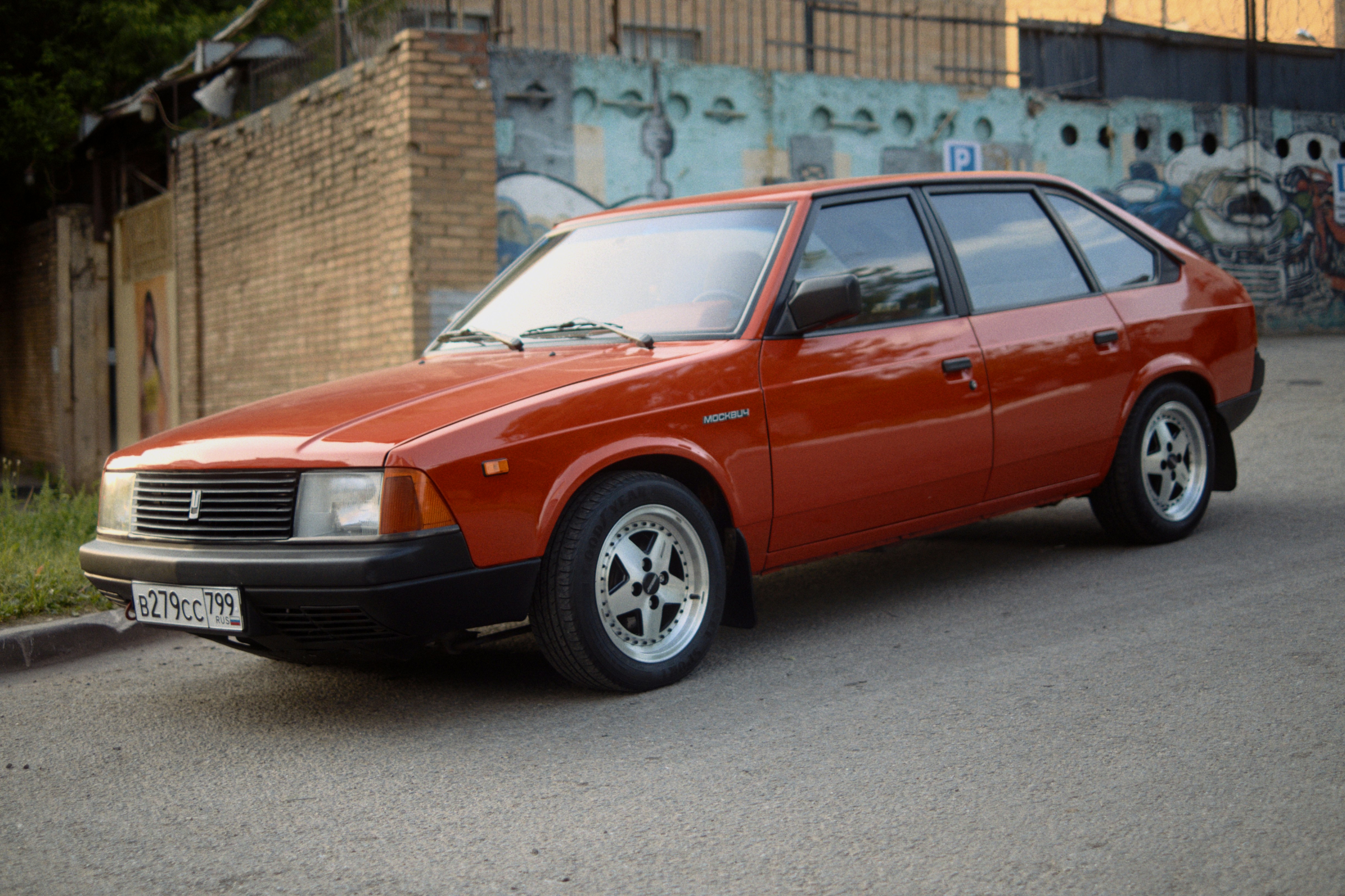 An old red car is parked on the street.