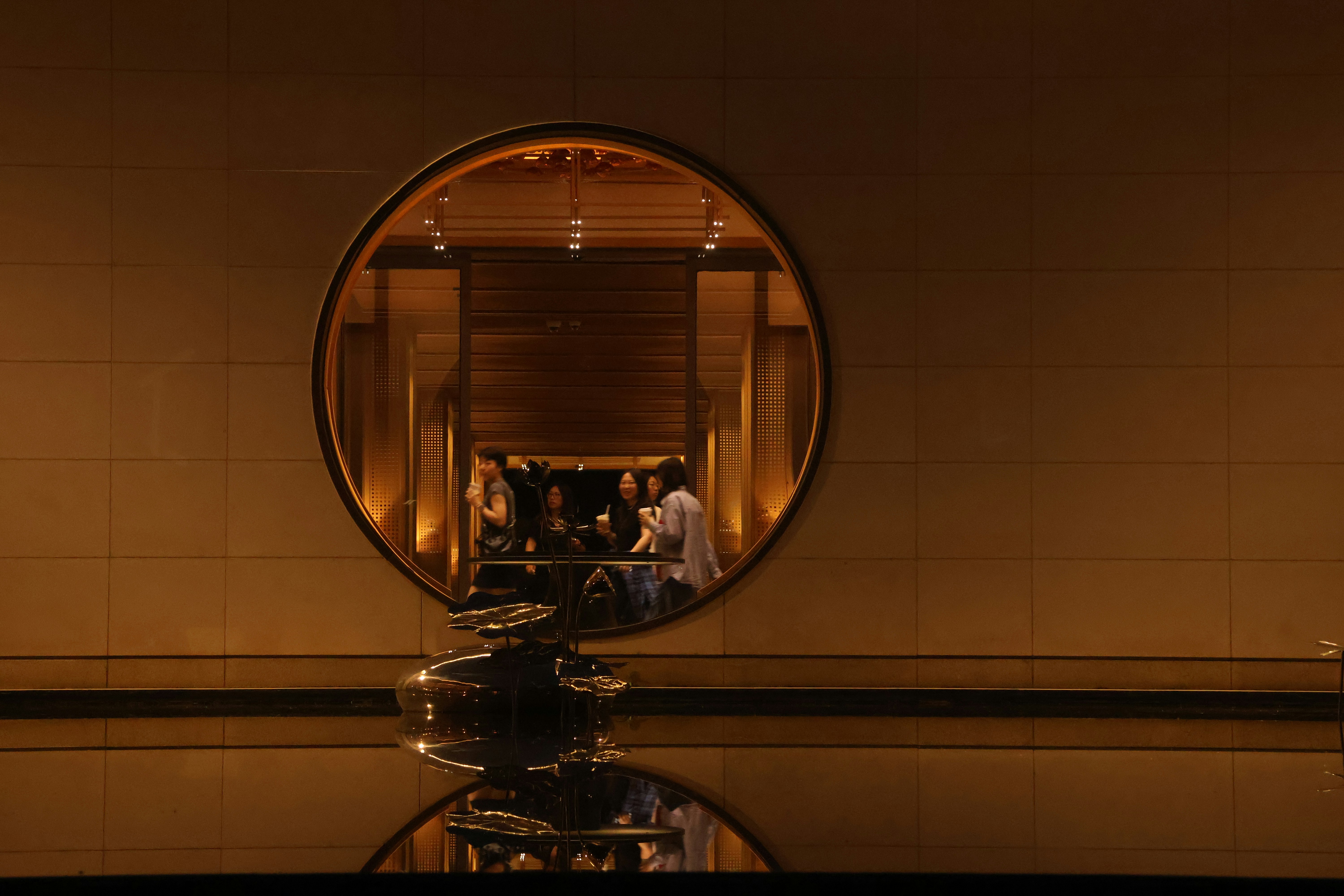 People dine inside a room, seen through a round window.